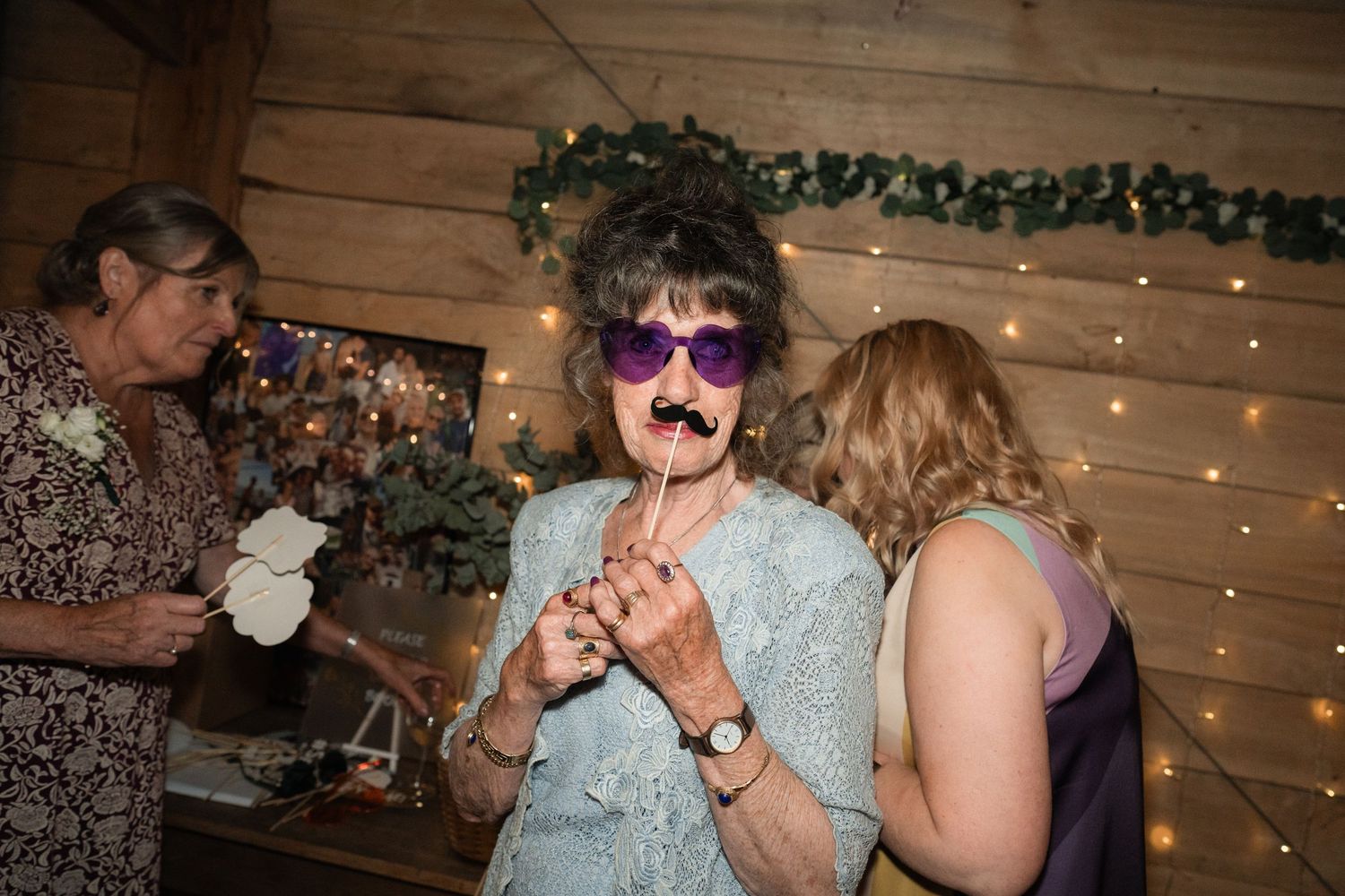 Wedding guests dancing and having fun at a reception with string lights glowing in the background.