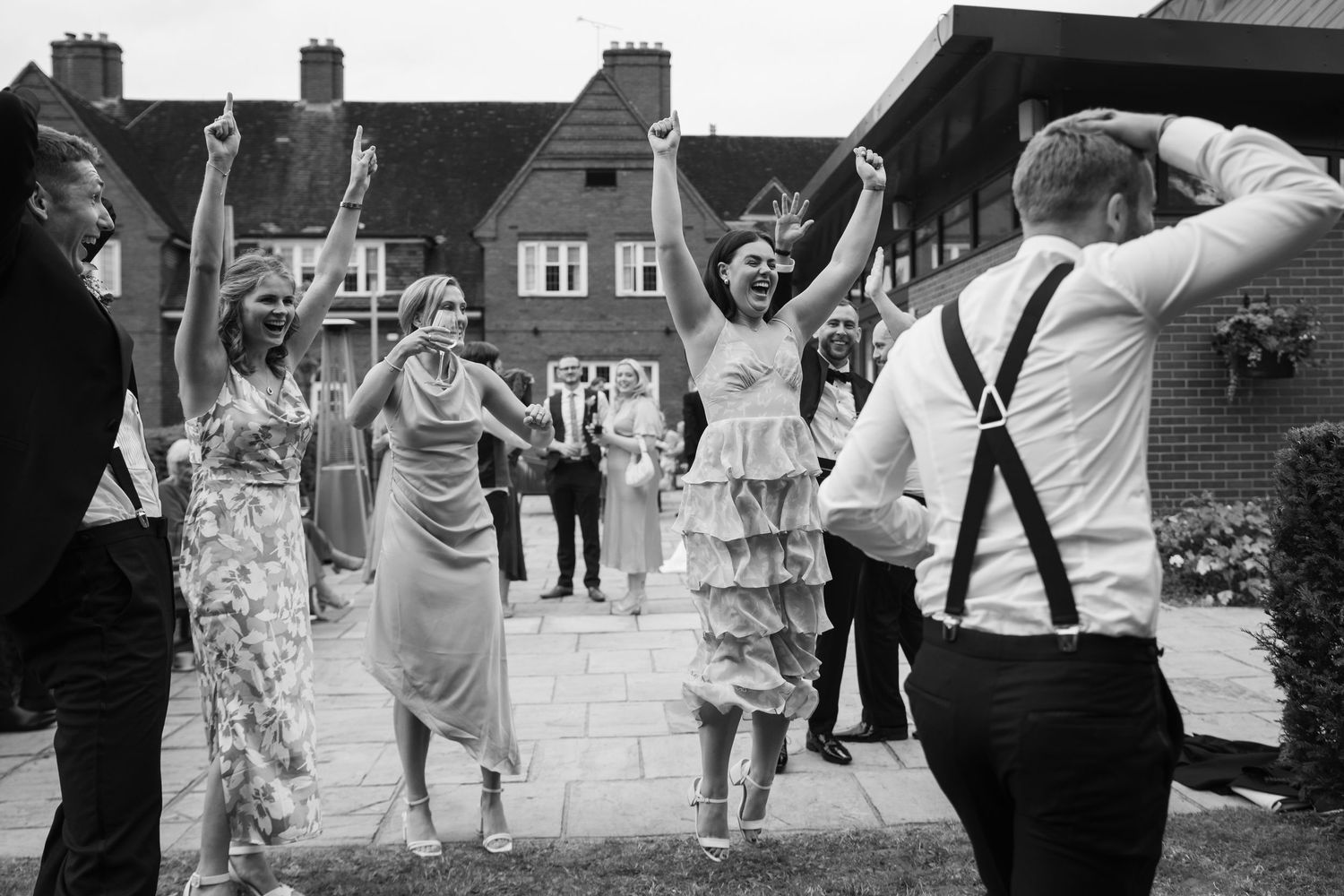 Wedding guests dancing and celebrating outdoors.