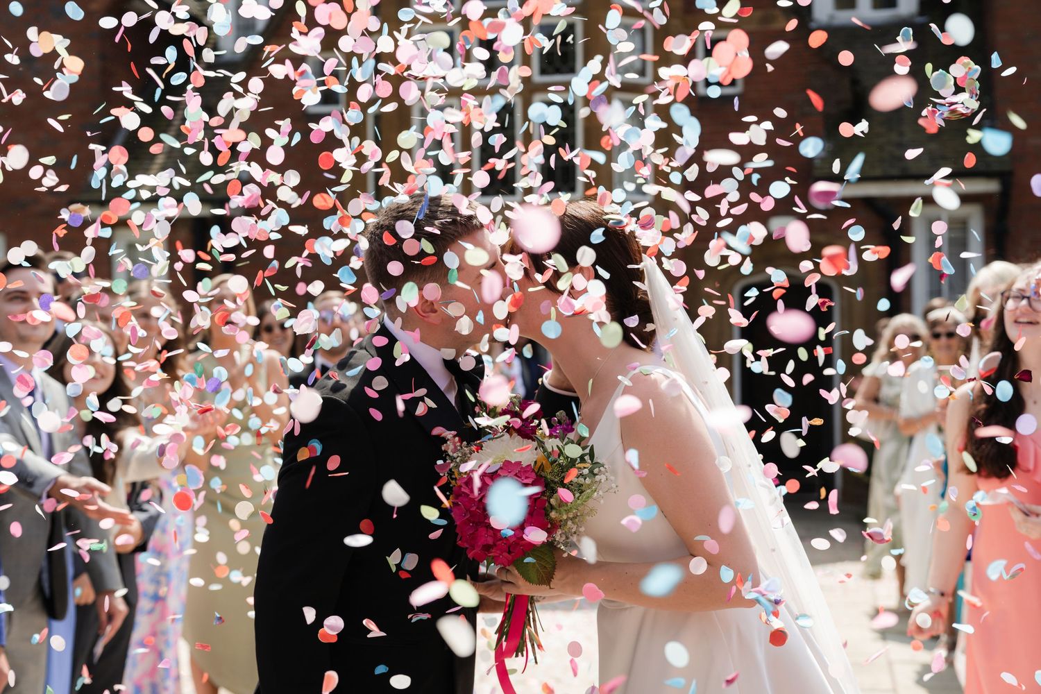 Confetti and rose petals shower down during a joyful wedding celebration.