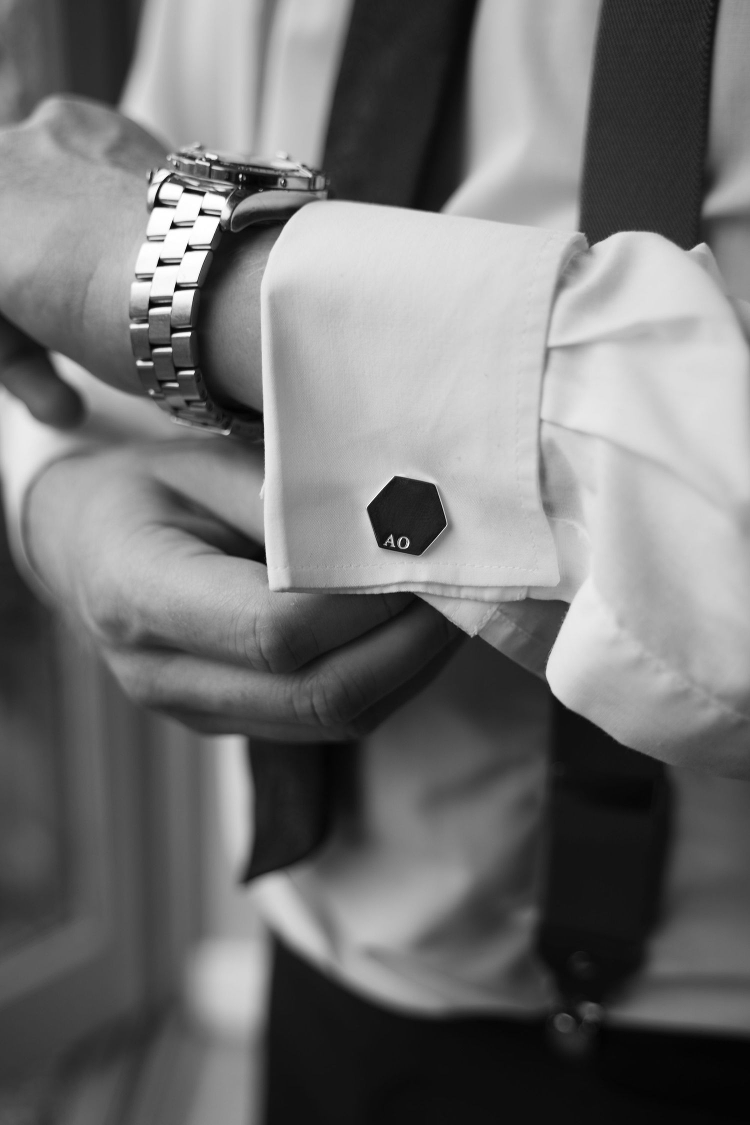 Close-up black and white image of hands adjusting a silver metal watch bracelet link.