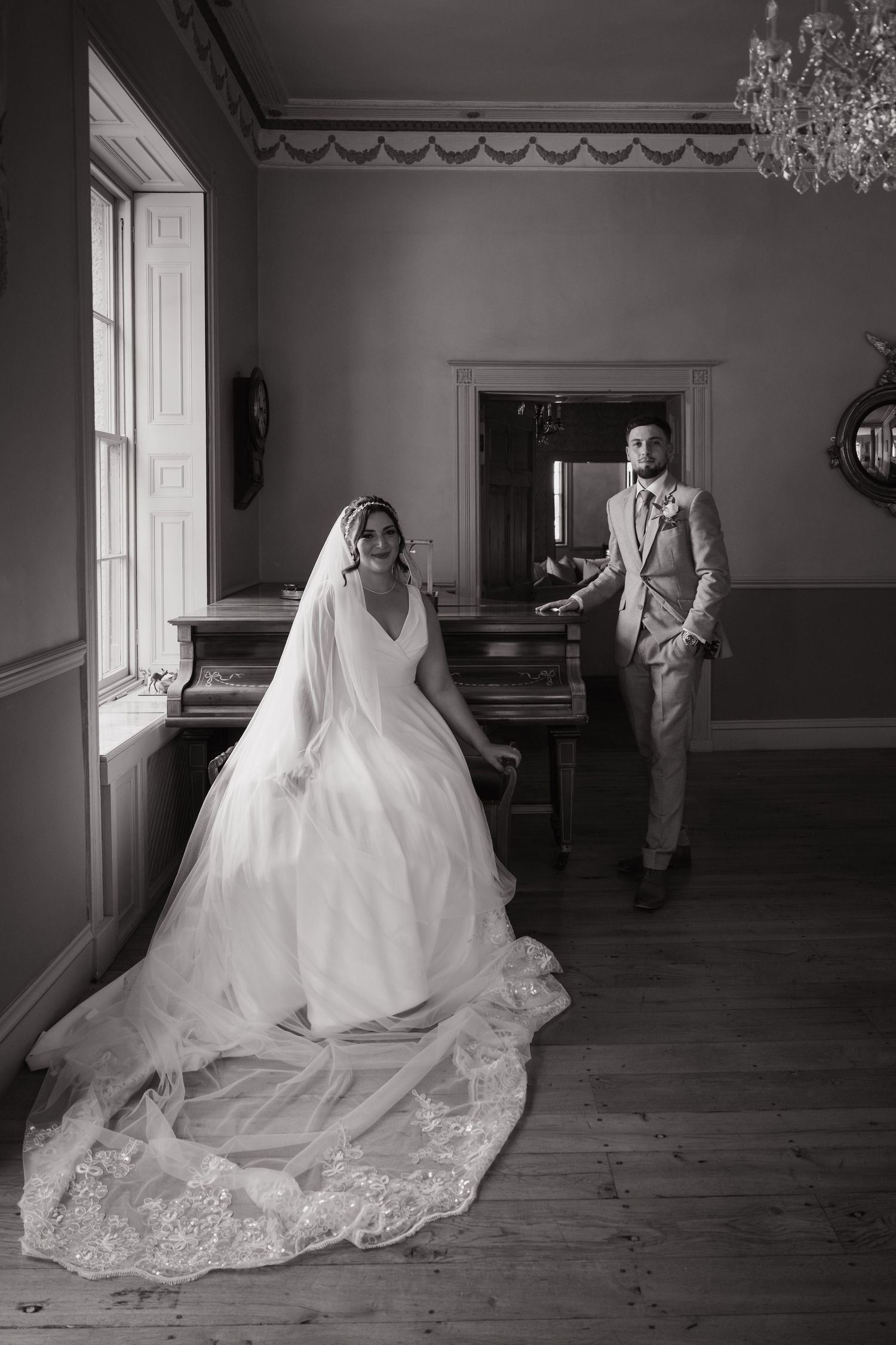 A series of black and white wedding photos showing a bride in a flowing lace gown with a dramatic train in an elegant room.