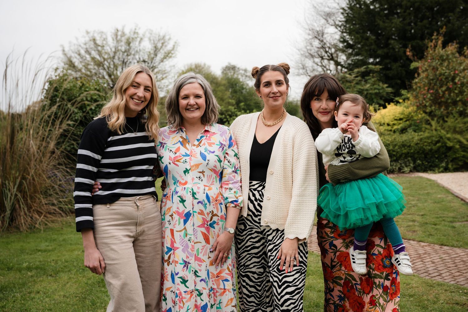 A group of people standing together outdoors in casual attire on a sunny day.