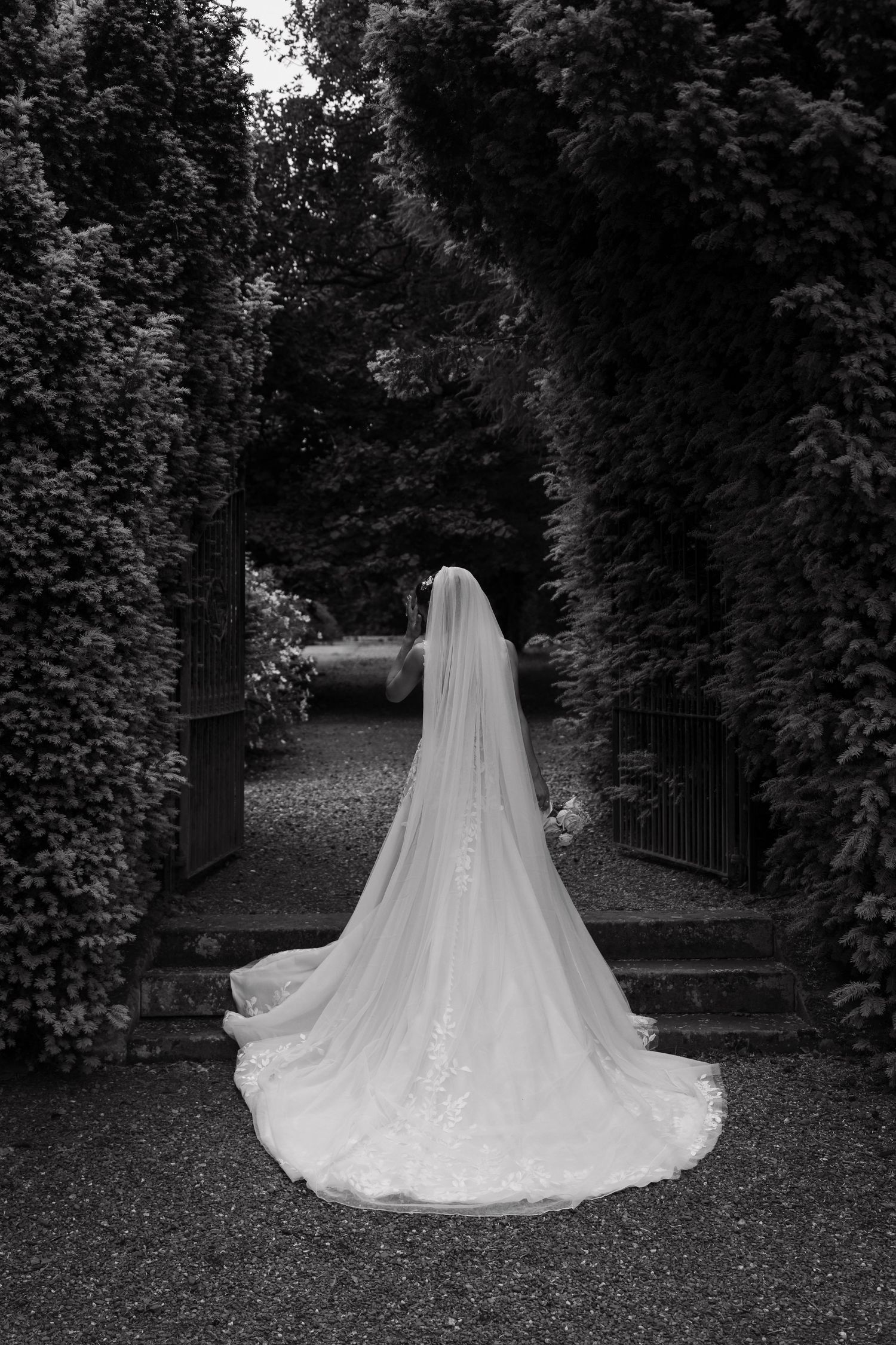 Dramatic black and white photo of wedding dress train in garden setting.