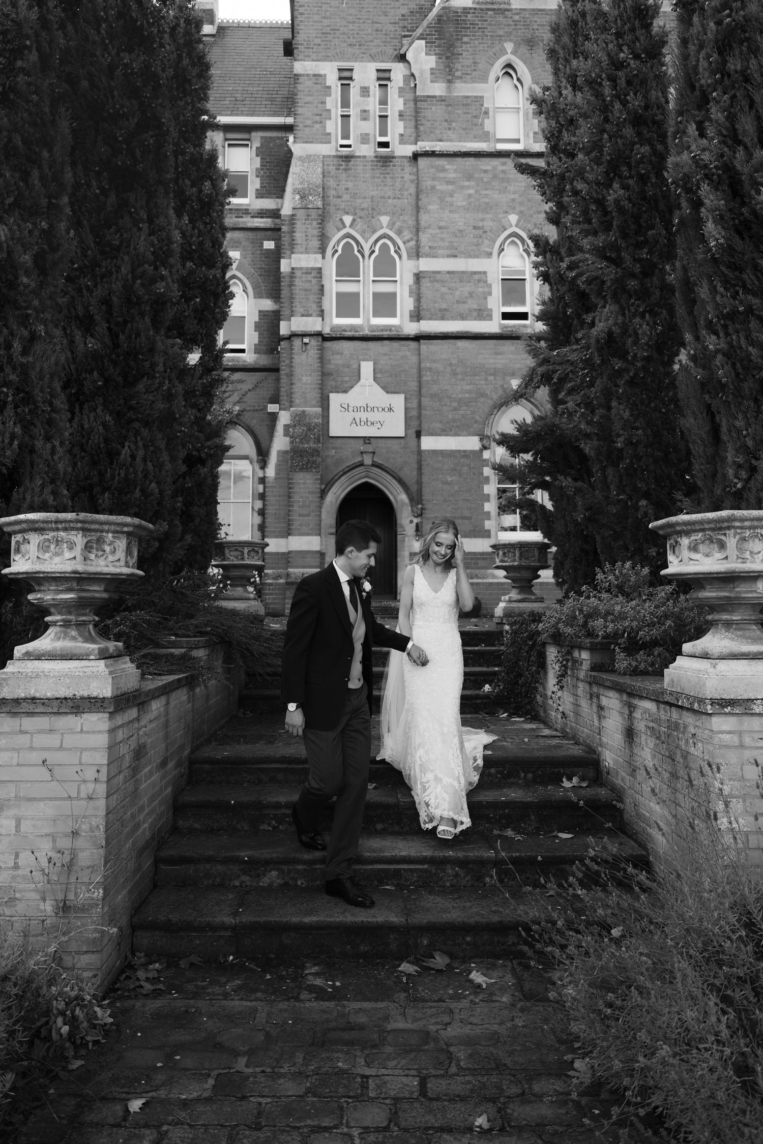 A series of black and white photos showing a couple walking up stone church steps in wedding attire.