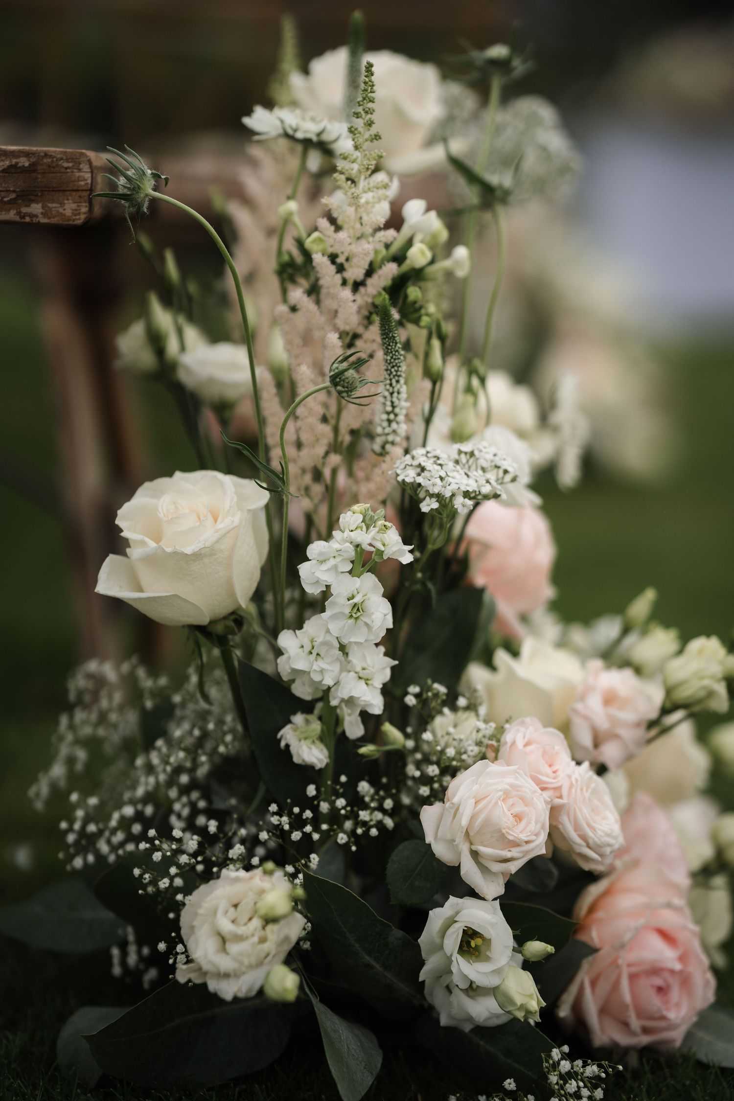 Romantic wedding floral arrangement featuring blush pink roses, white baby's breath, and delicate greenery.