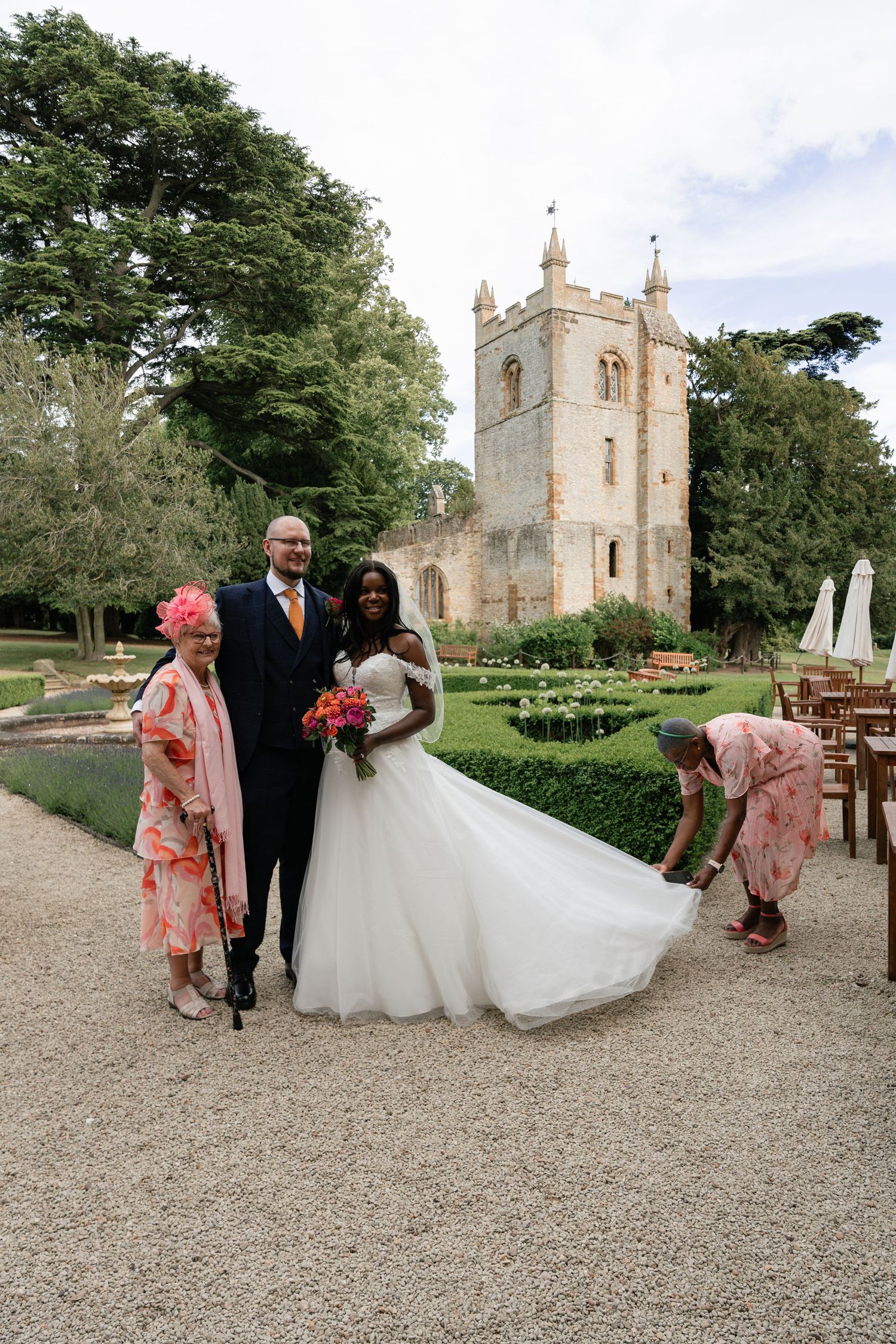 Wedding party walking on gravel path with historic church building in background.