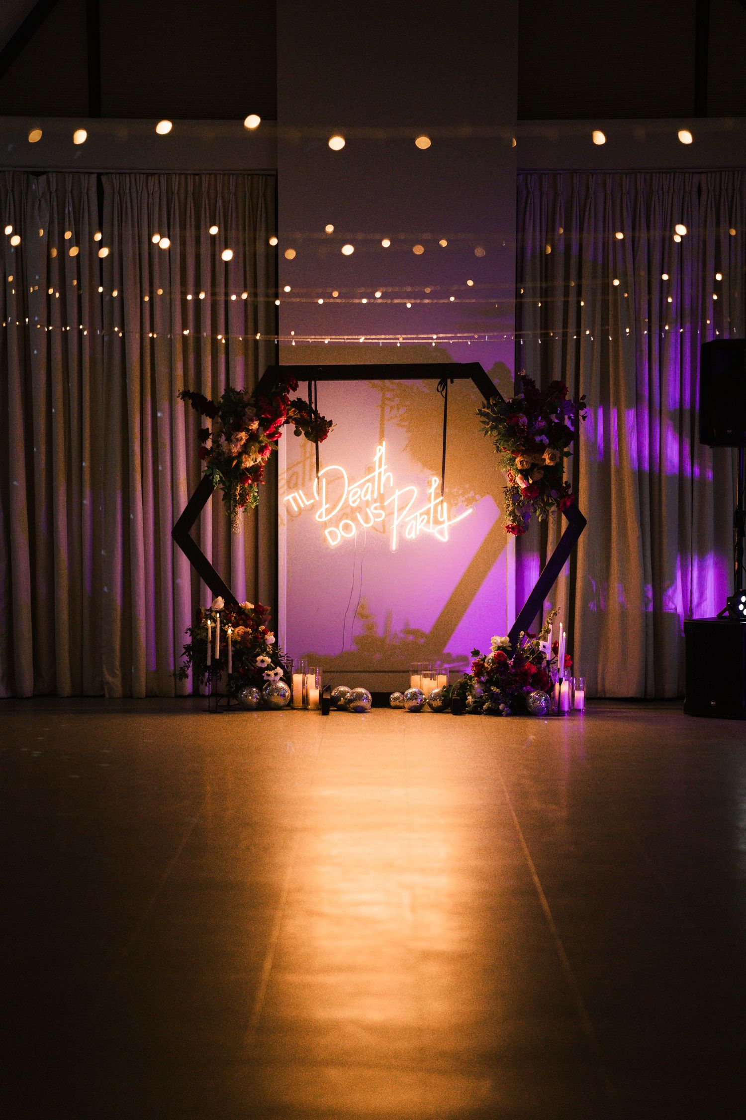 Dark stage illuminated with purple lighting and string lights overhead, creating a moody performance atmosphere.