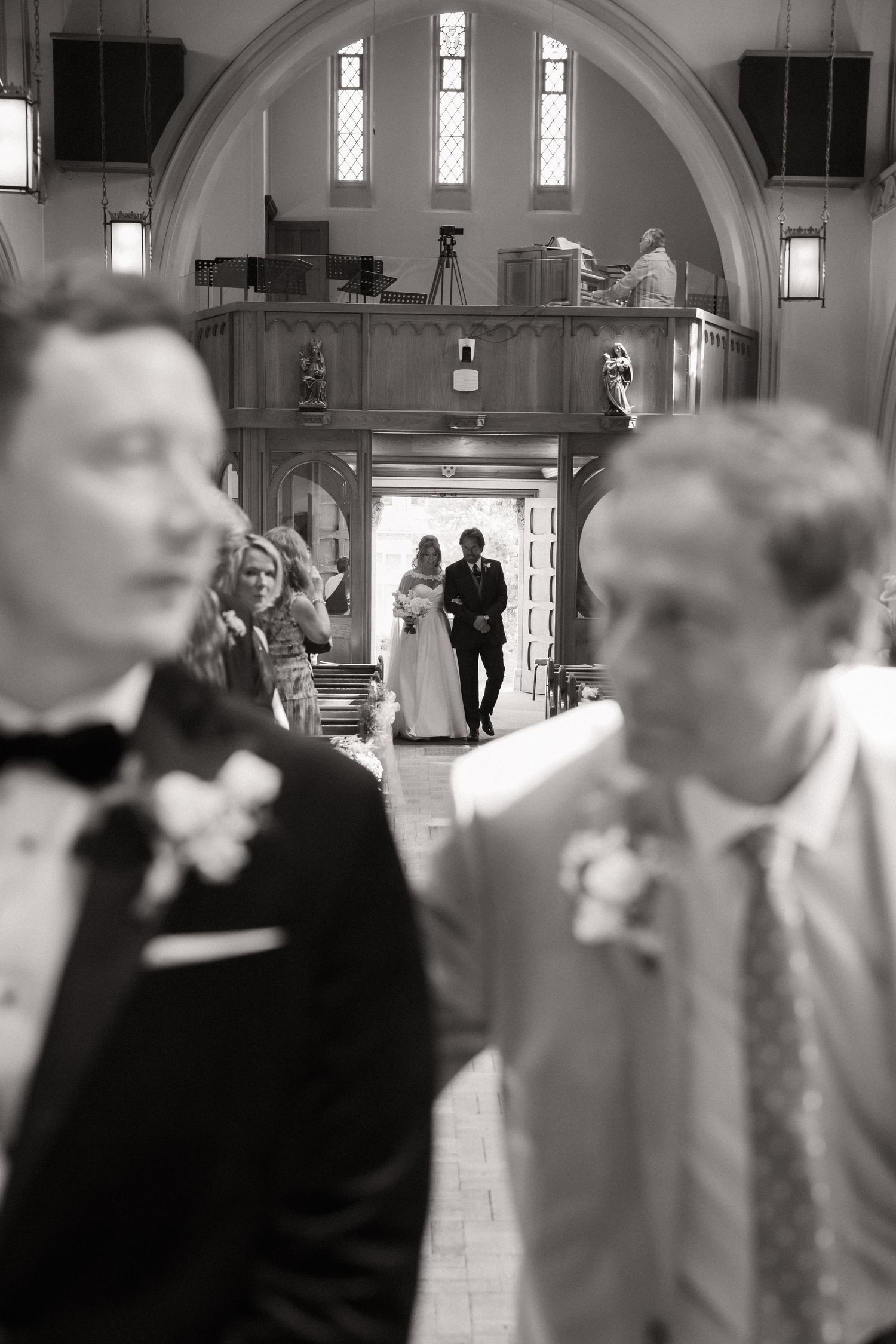 A black and white photo of people gathered inside a church or cathedral with arched architecture.