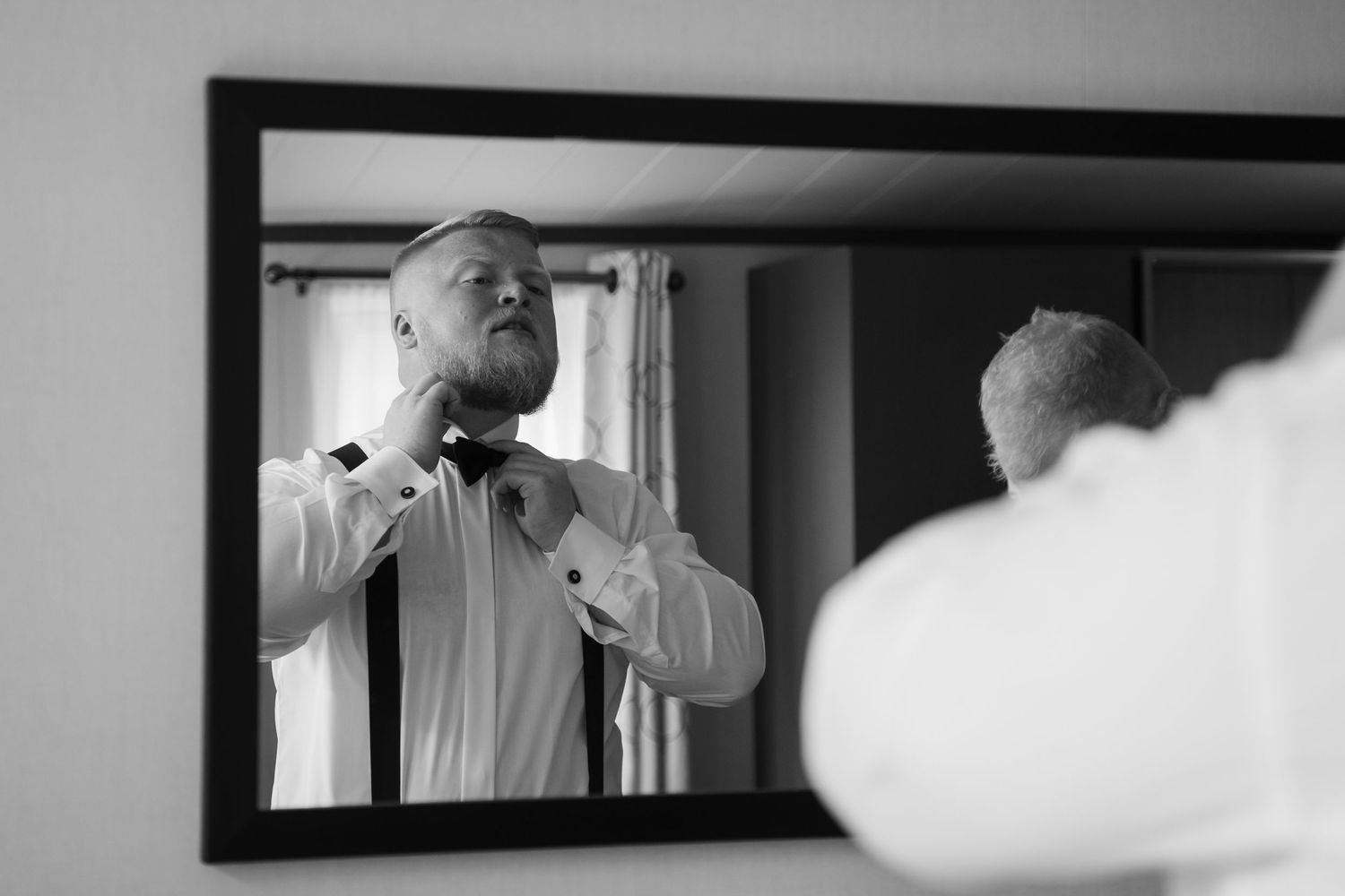 Black and white photo series showing someone getting ready and adjusting their tie in a bathroom mirror.
