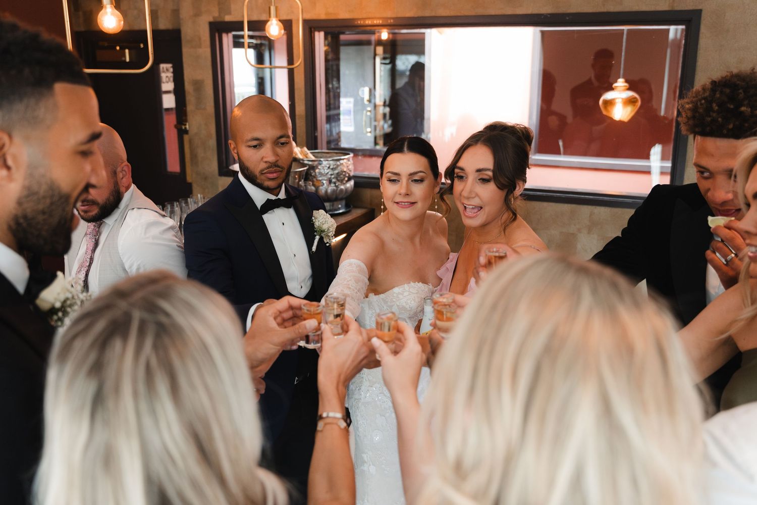 Wedding guests raise champagne glasses in a celebratory toast during an indoor reception.