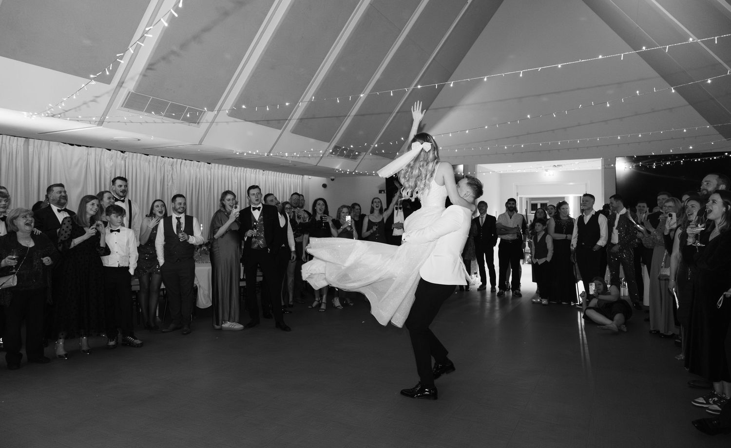 Wedding guests dance and celebrate during a joyous reception in an elegant white tent venue.