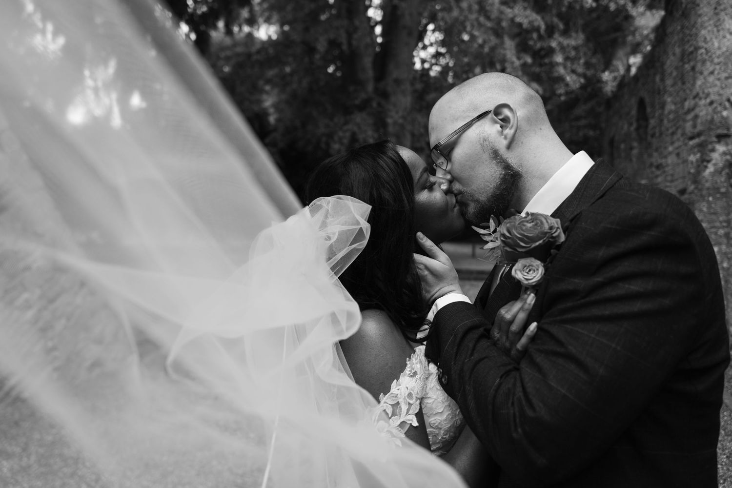 A romantic black and white wedding photo series showing intimate moments between a bride and groom in formal attire.