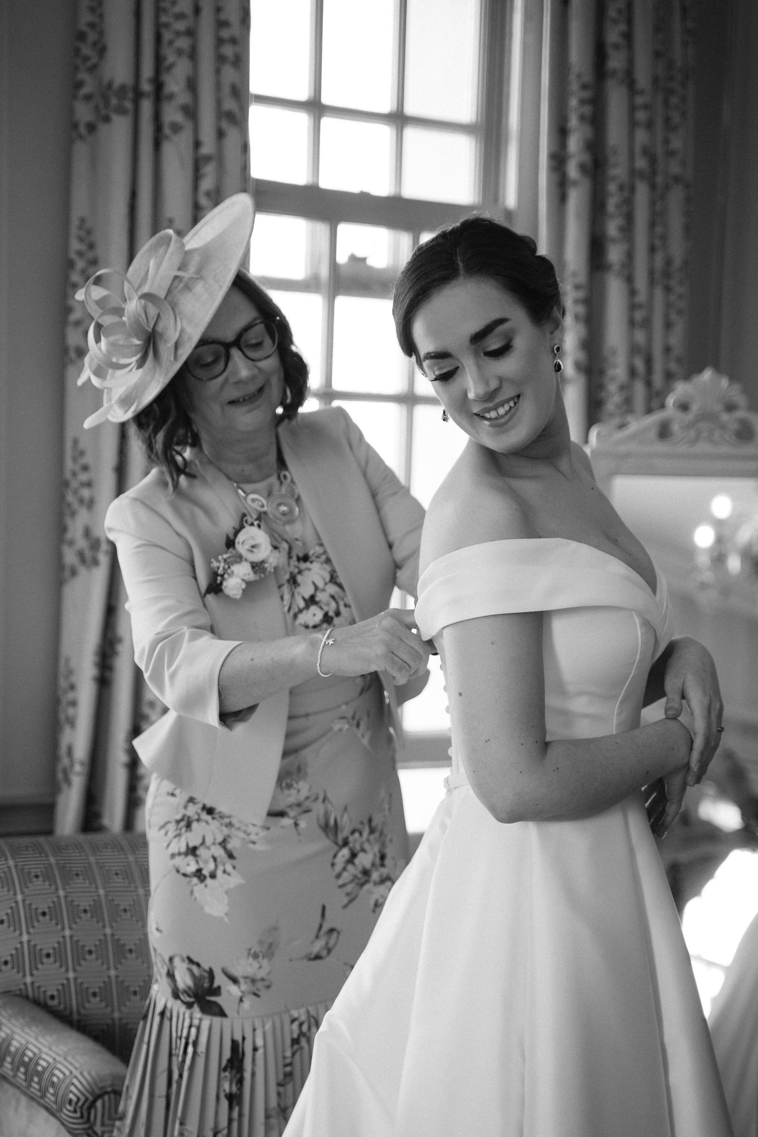 Black and white photo series showing a bride getting ready in an elegant room with floral curtains and natural light.