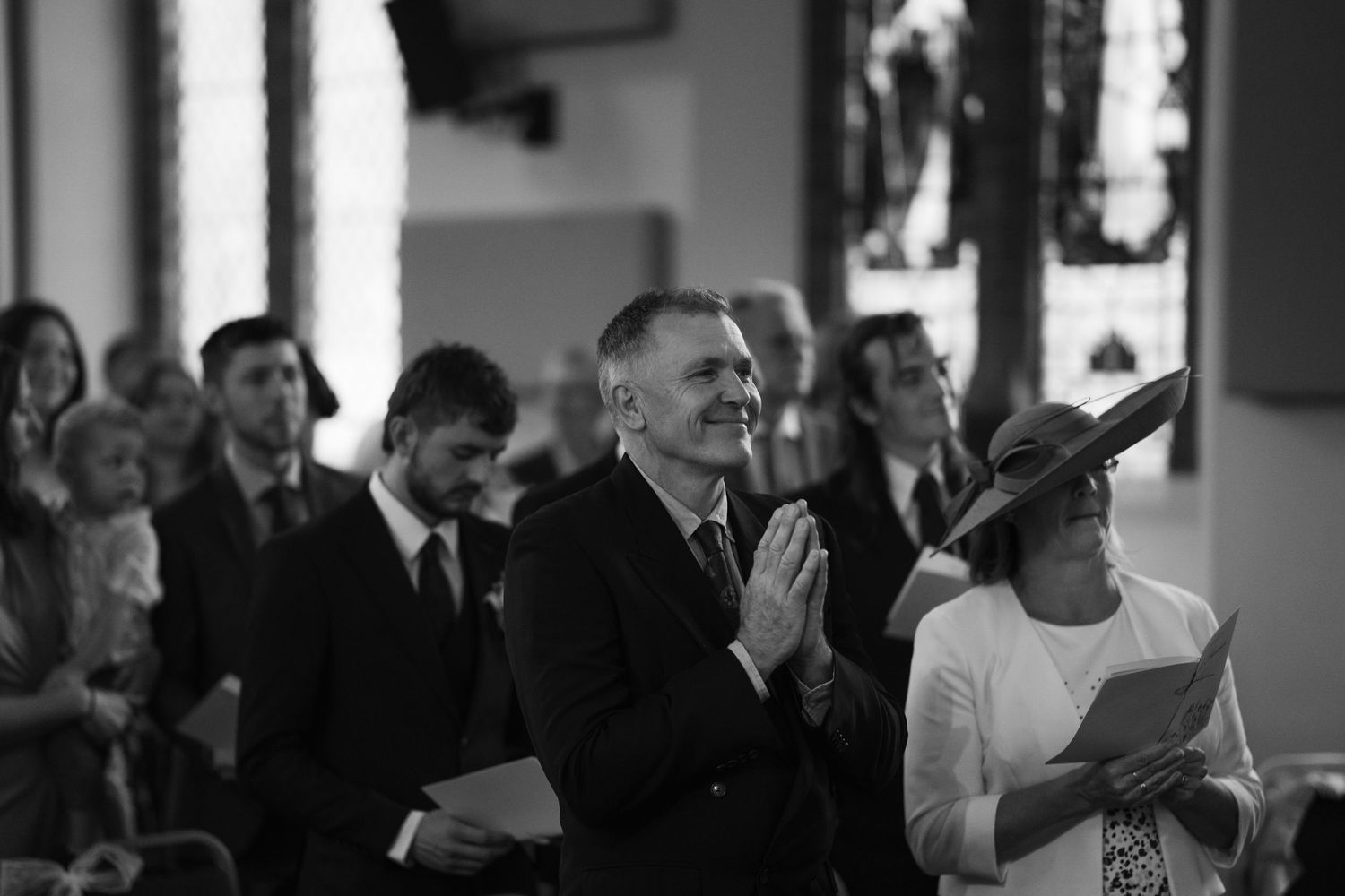 Wedding guests react emotionally during an indoor ceremony.