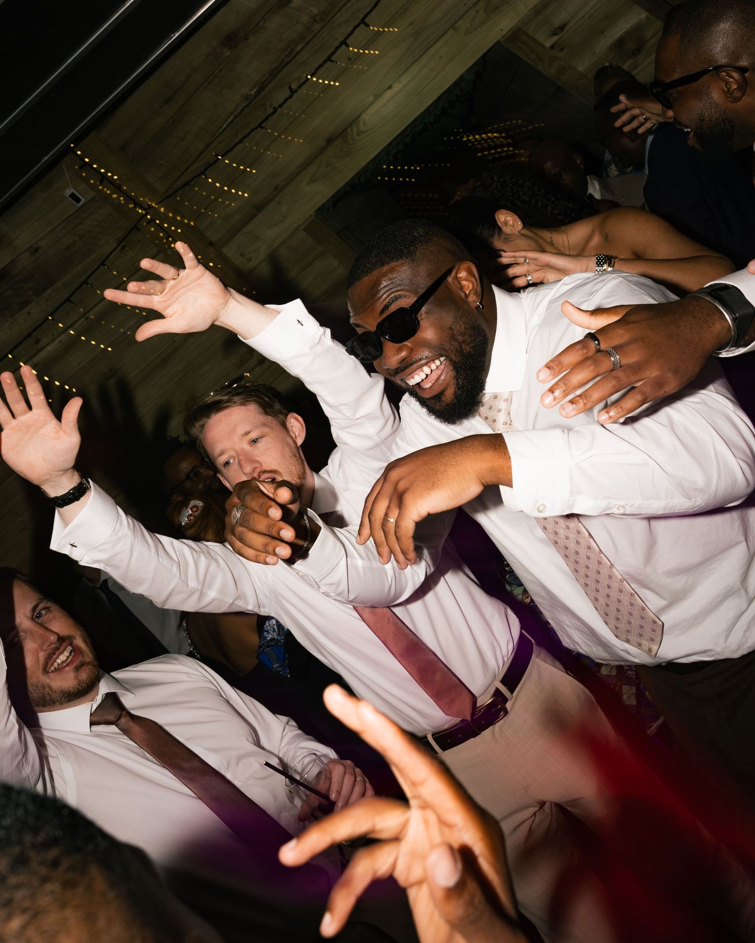 Excited groomsmen dancing and celebrating at a lively wedding reception party.