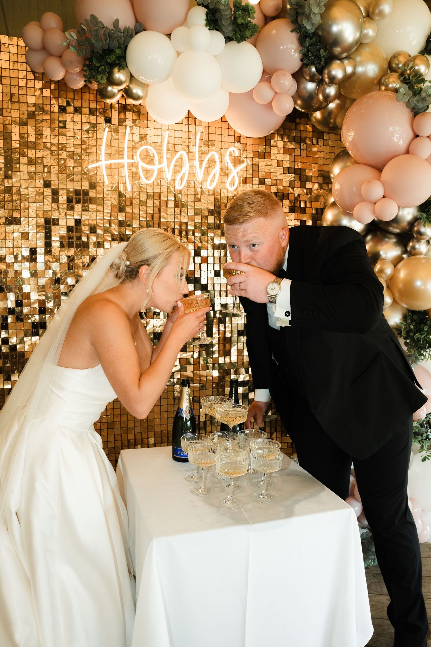 Romantic wedding sequence showing couple sharing champagne toast under glittering gold backdrop and pink balloon arch.