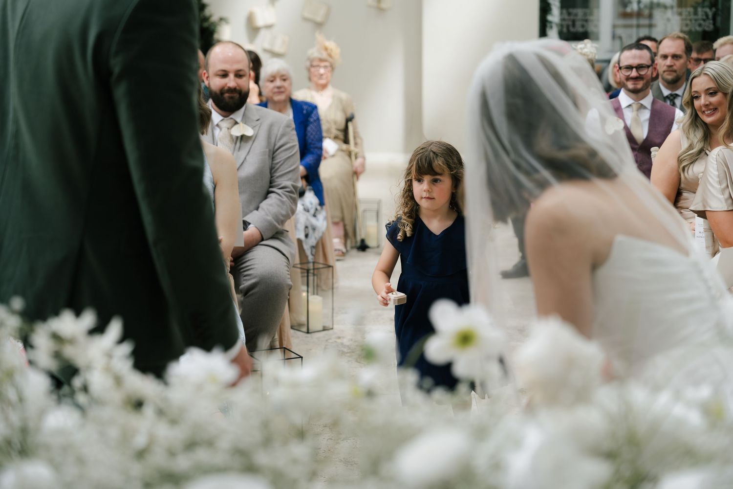 Wedding guests mingle and celebrate during an elegant reception decorated with white floral arrangements.