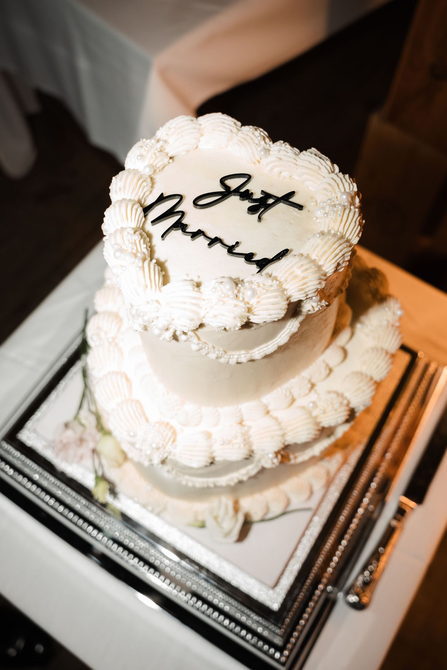 A series of five identical white frosted cakes with decorative piping displayed on a dark surface.