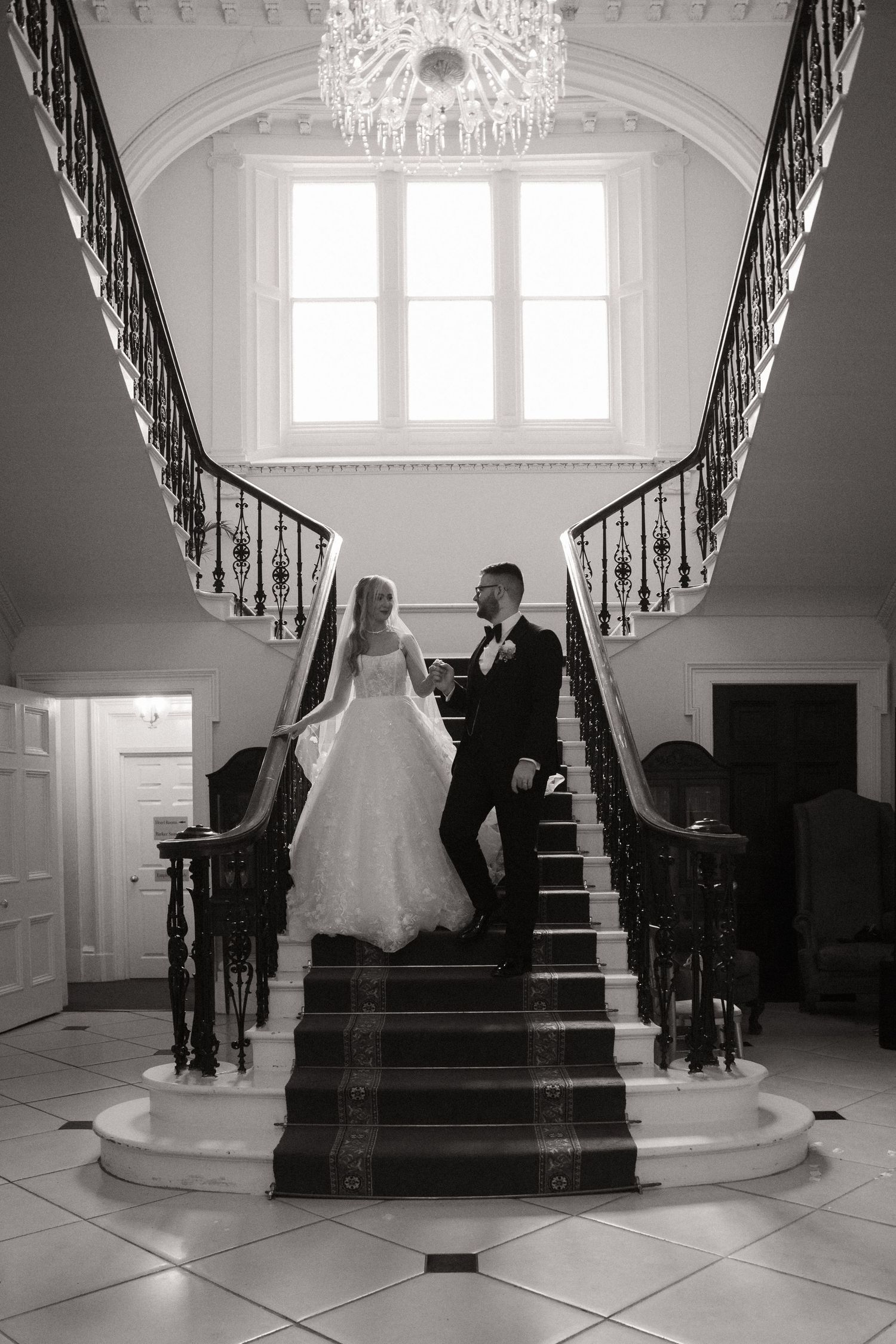 A series of five black and white photos showing a grand staircase with an elegant chandelier in a formal entryway.