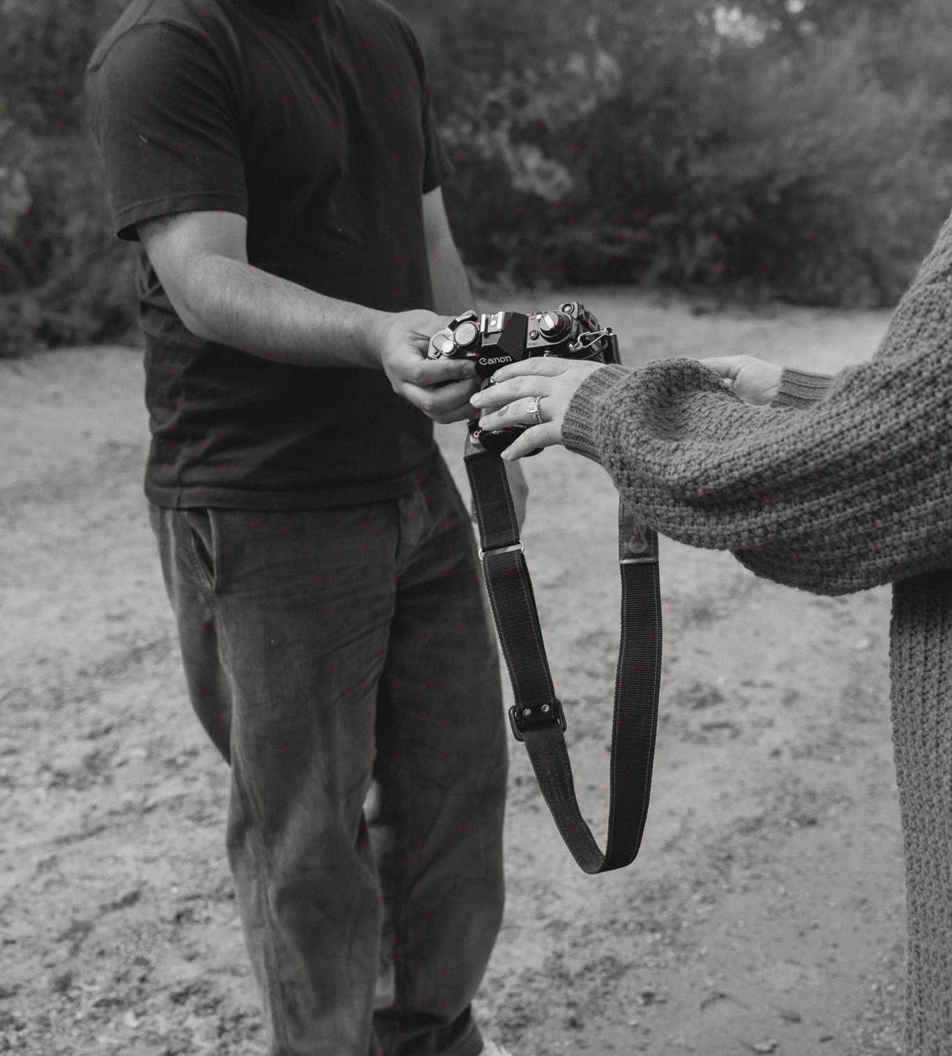 Black and white photo of people handling a vintage camera outdoors.