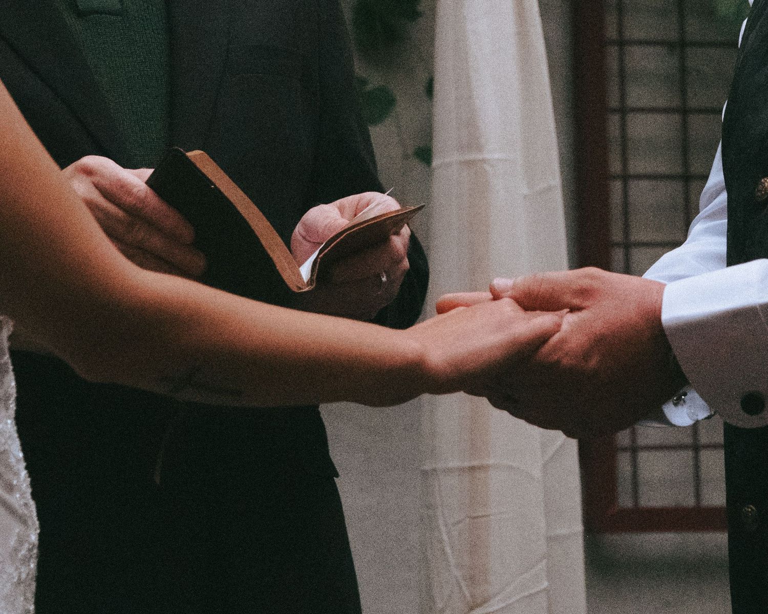 Two people hold hands in a romantic moment during their wedding ceremony.