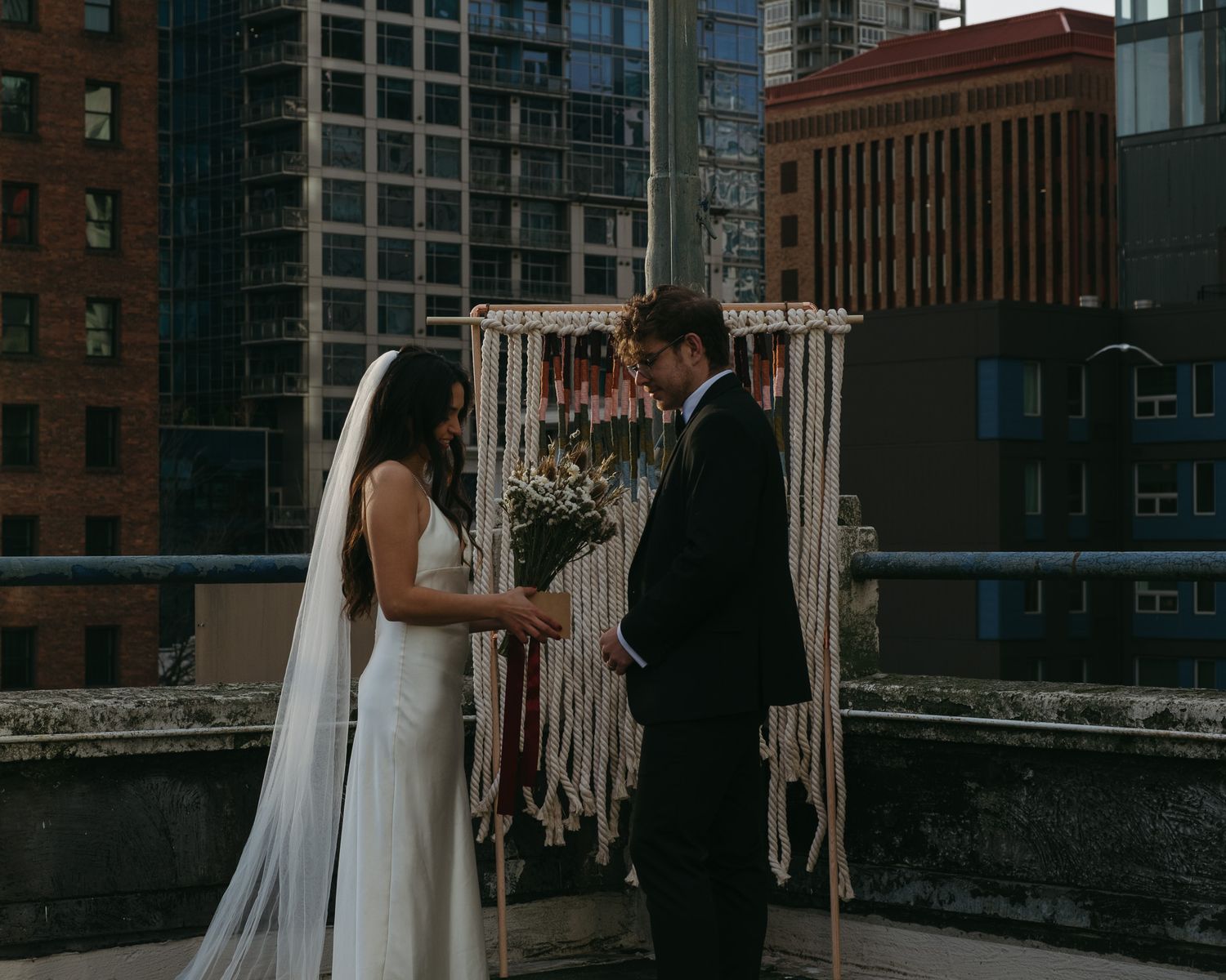A romantic wedding photo sequence showing a couple embracing on an urban rooftop with brick buildings in the background.