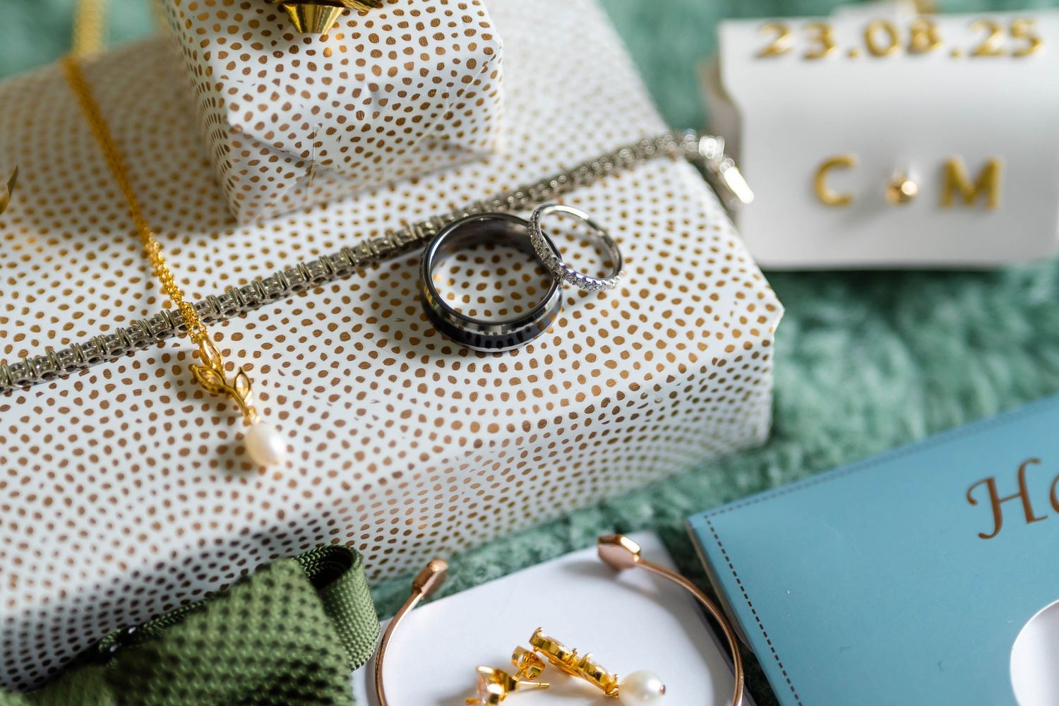 Wedding accessories and jewelry arranged on turquoise velvet surface.