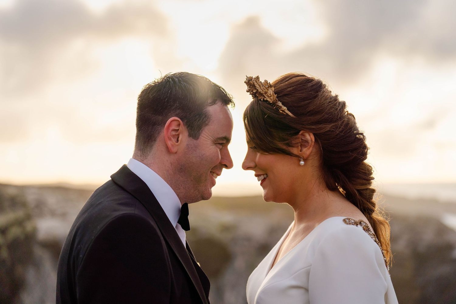 Romantic sunset wedding portrait with couple in elegant attire.