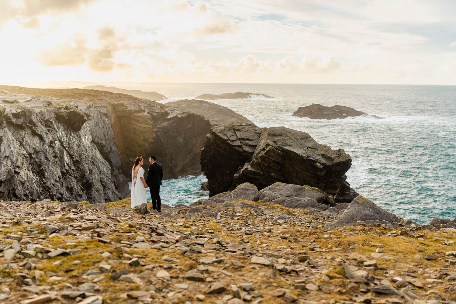 Rugged coastline with waves crashing against rocky cliffs during golden hour.