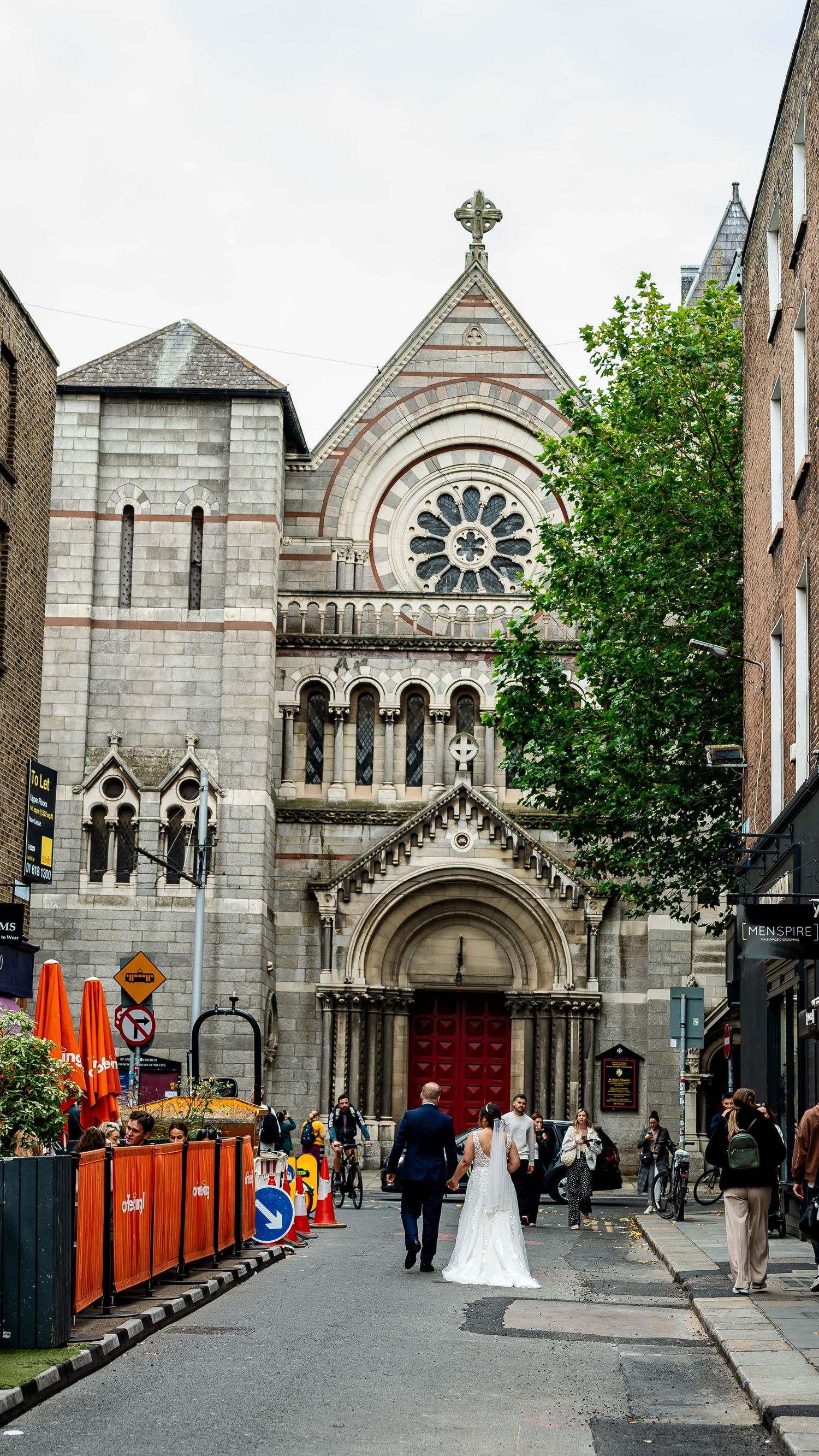 Gothic stone church facade with ornate details and arched entrances on a city street.