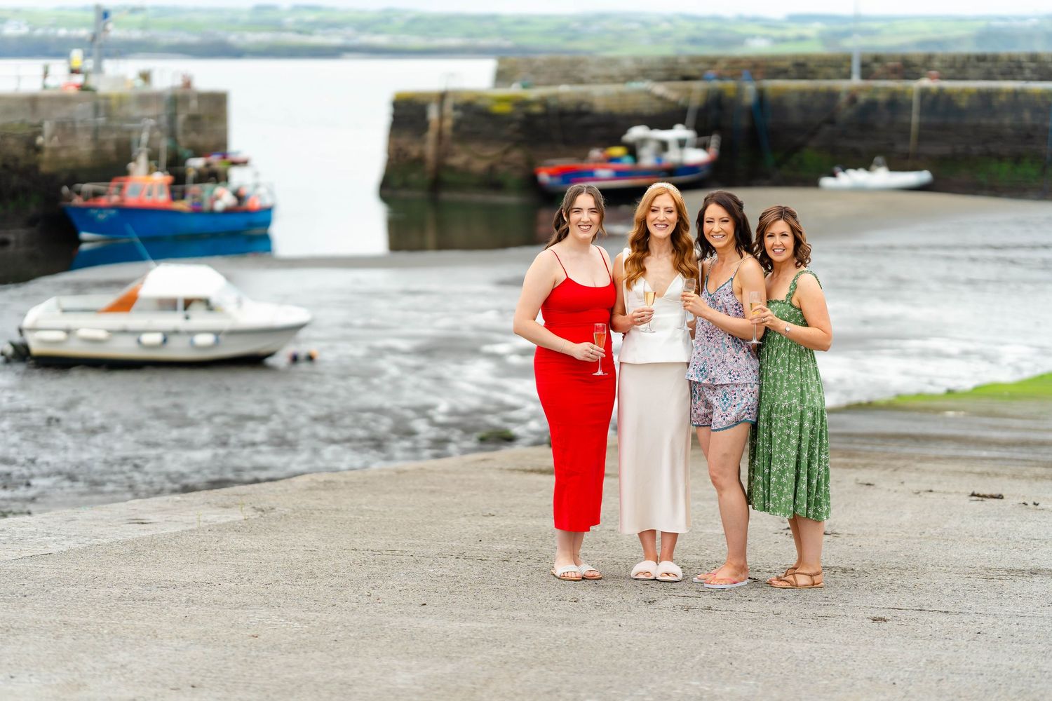 A group poses together on a waterfront walkway near boats and stone walls.
