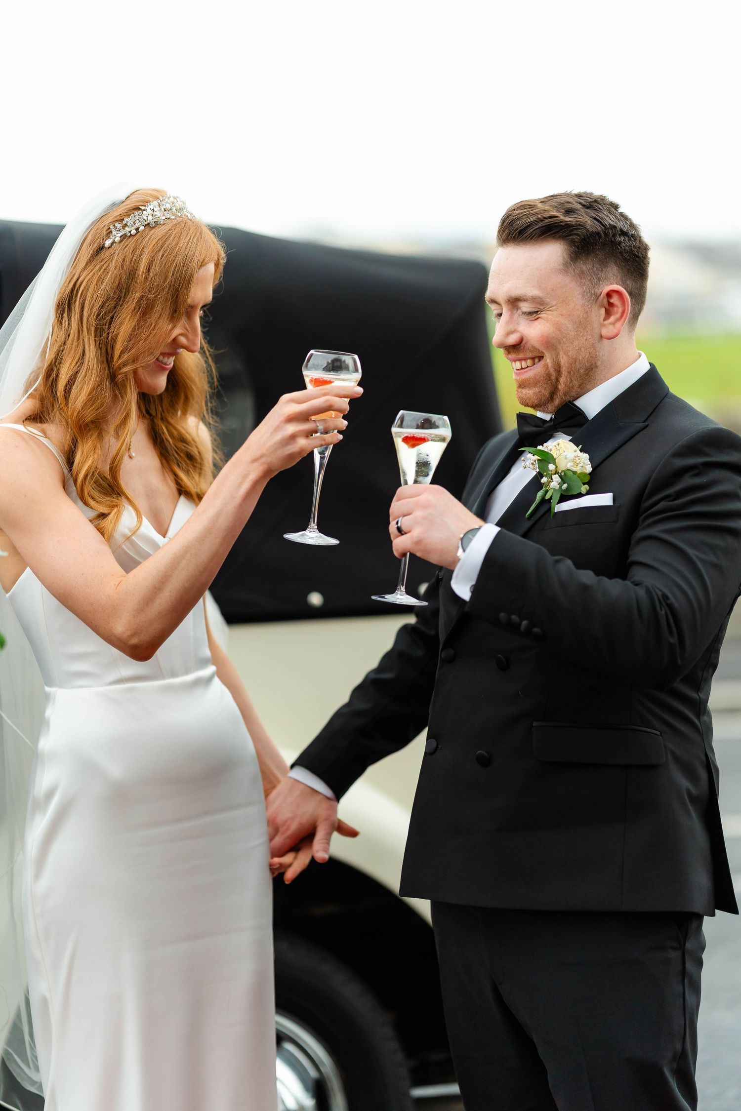 Wedding couple toasting with champagne glasses in formal attire.