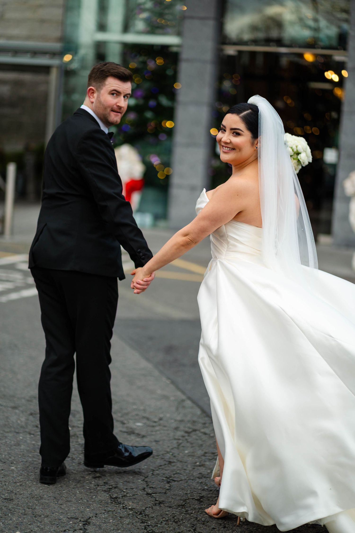 Newlyweds dance and twirl on a cobblestone street, bride's white dress flowing dramatically.
