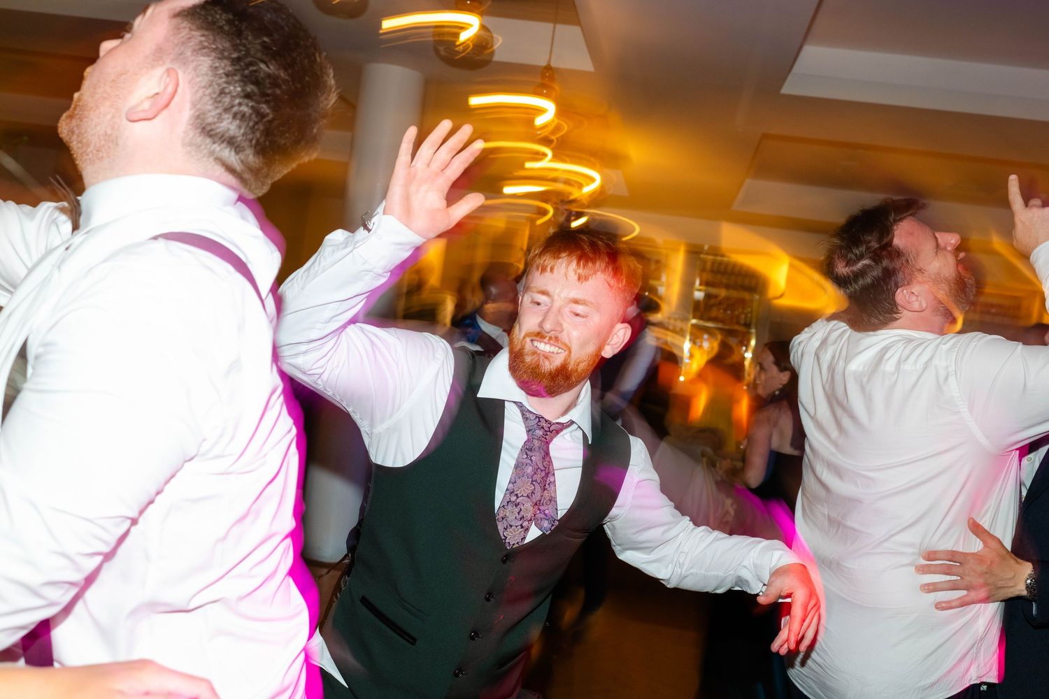 Energetic dancing and celebration captured in motion blur at indoor wedding reception.