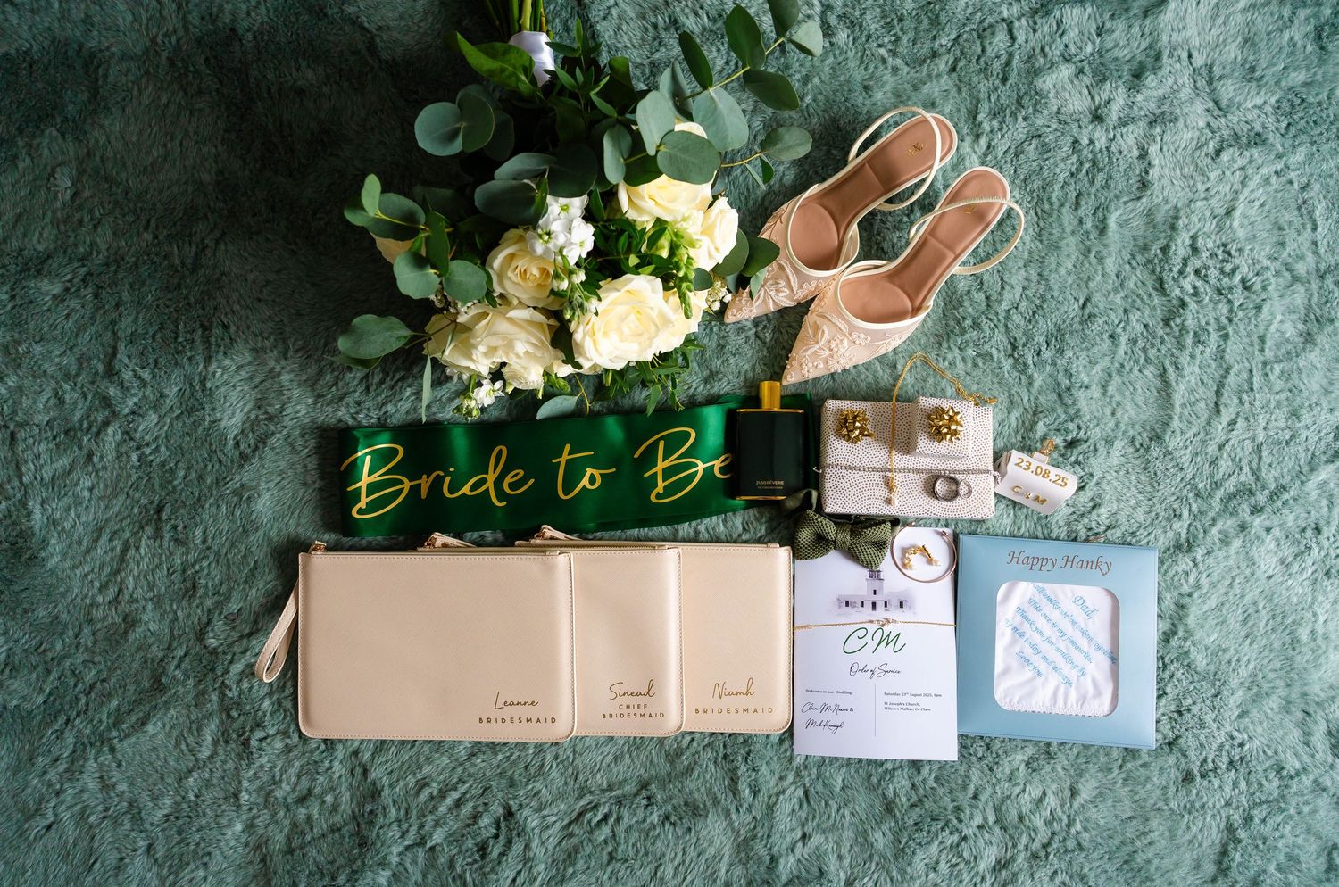 Wedding details including invitations and floral arrangements on turquoise textured surface.