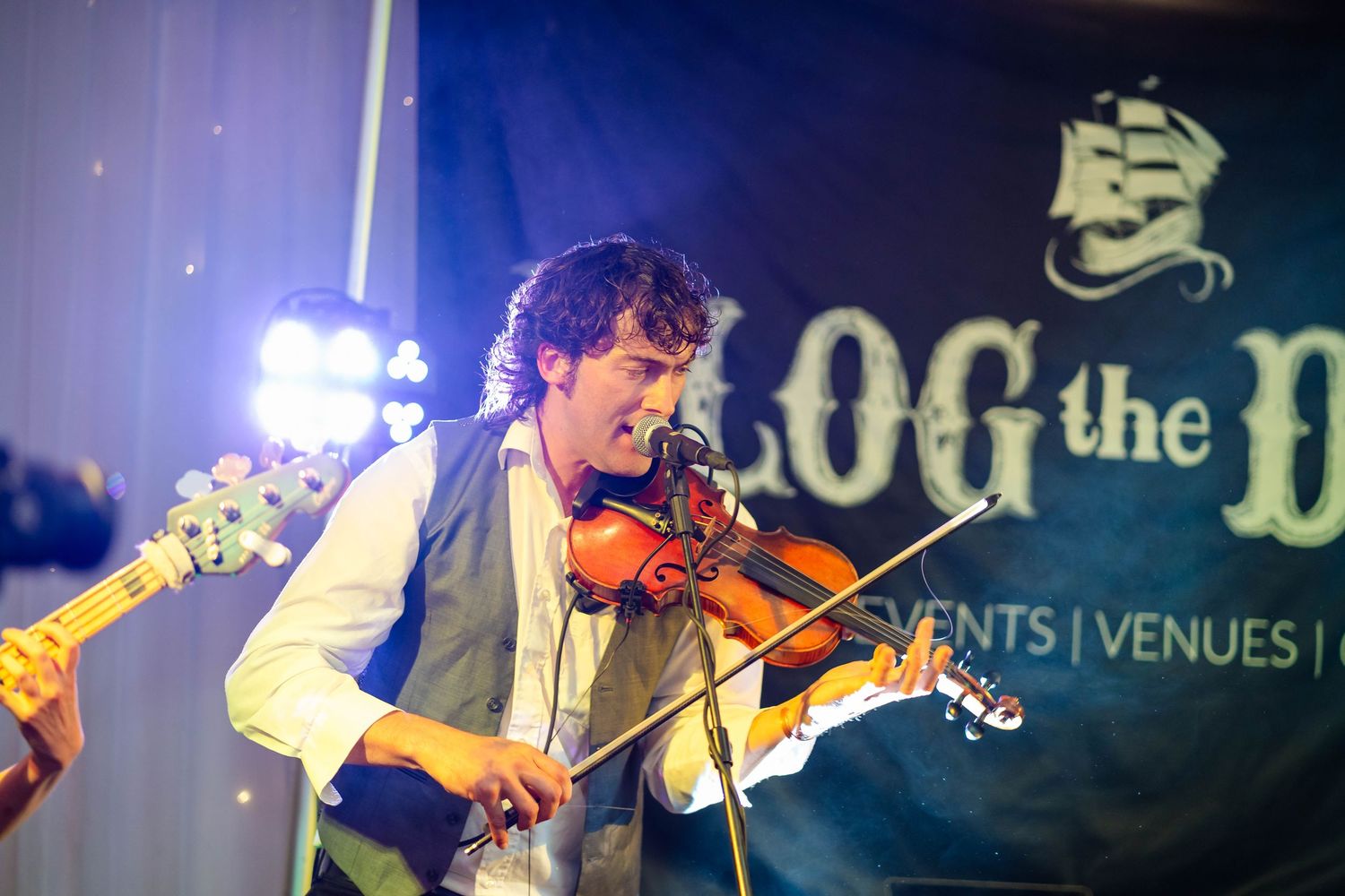 Band performs on stage with instruments at evening wedding reception.