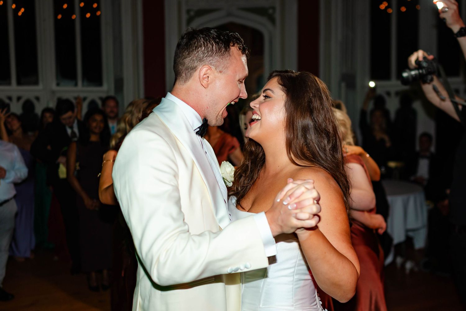 Wedding guests dancing and celebrating together on a lively dance floor during an evening reception.