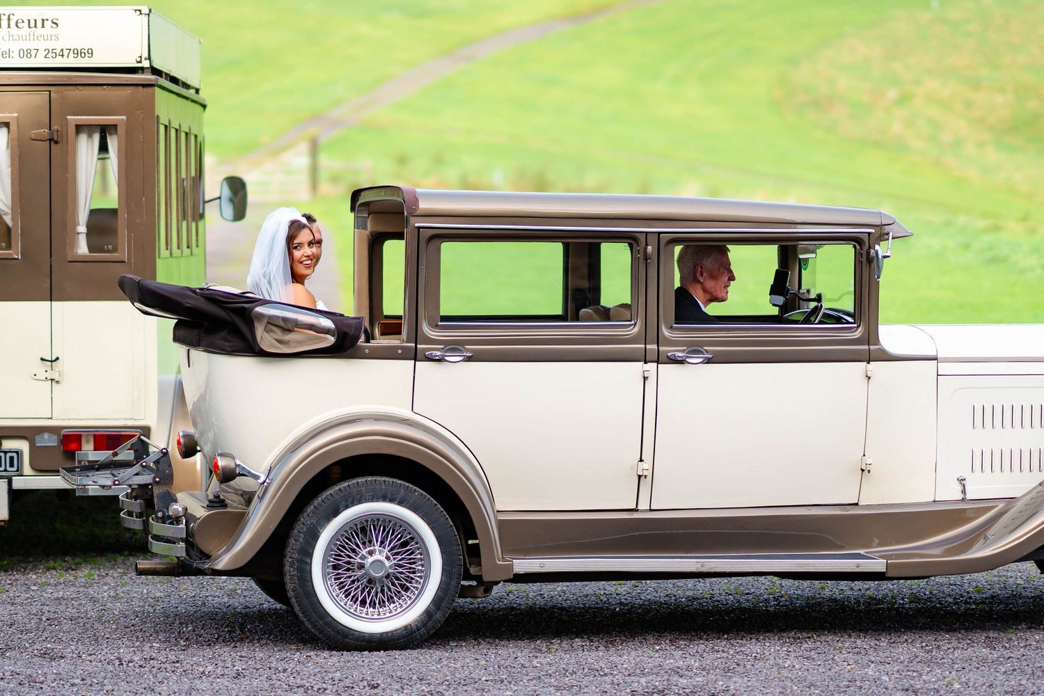 A row of vintage luxury automobiles from the 1920s and 1930s displayed on grass with elegant white wall tires and chrome details.