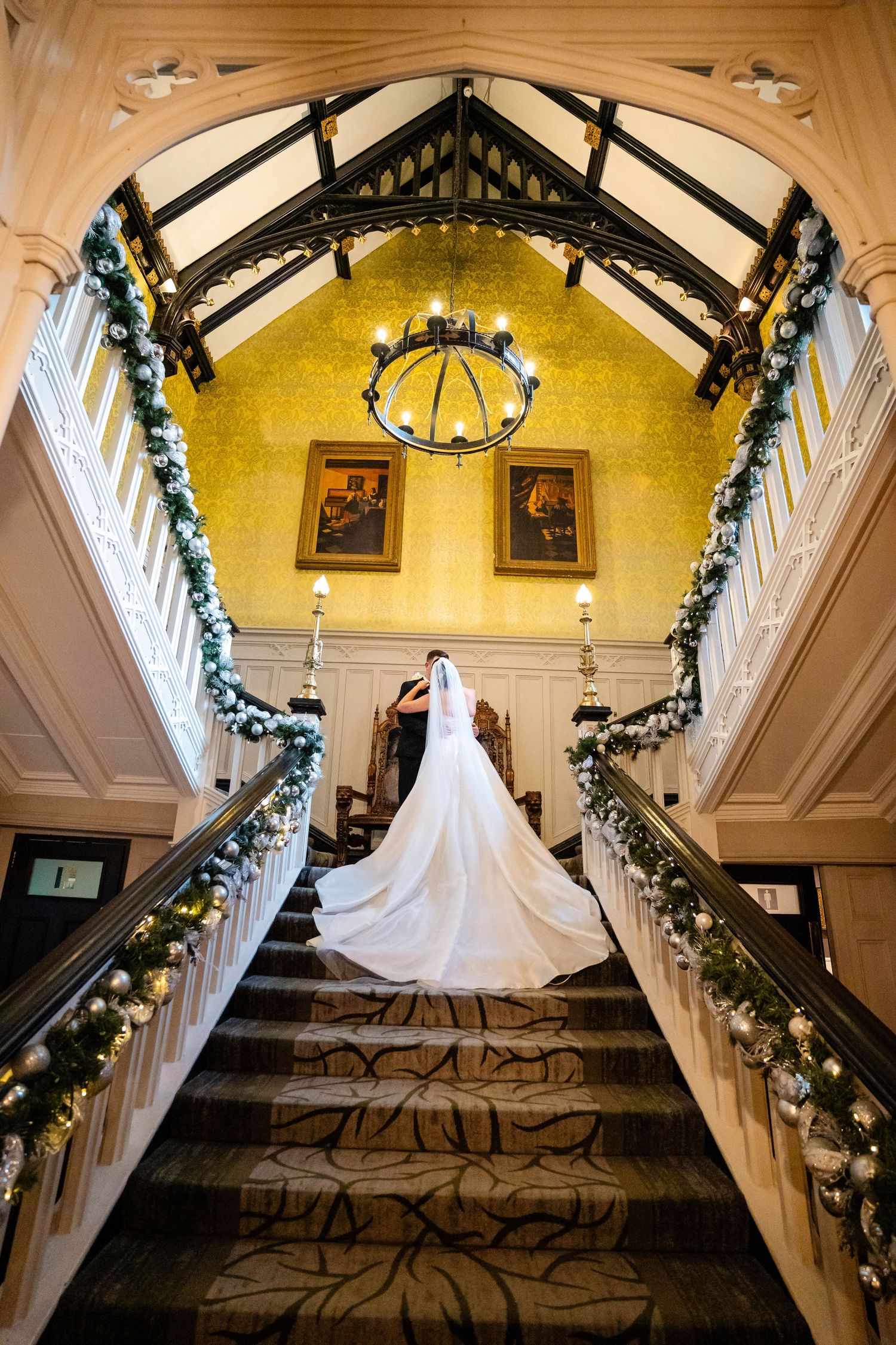 A majestic staircase with vaulted ceilings and holiday decor featuring a white wedding gown.