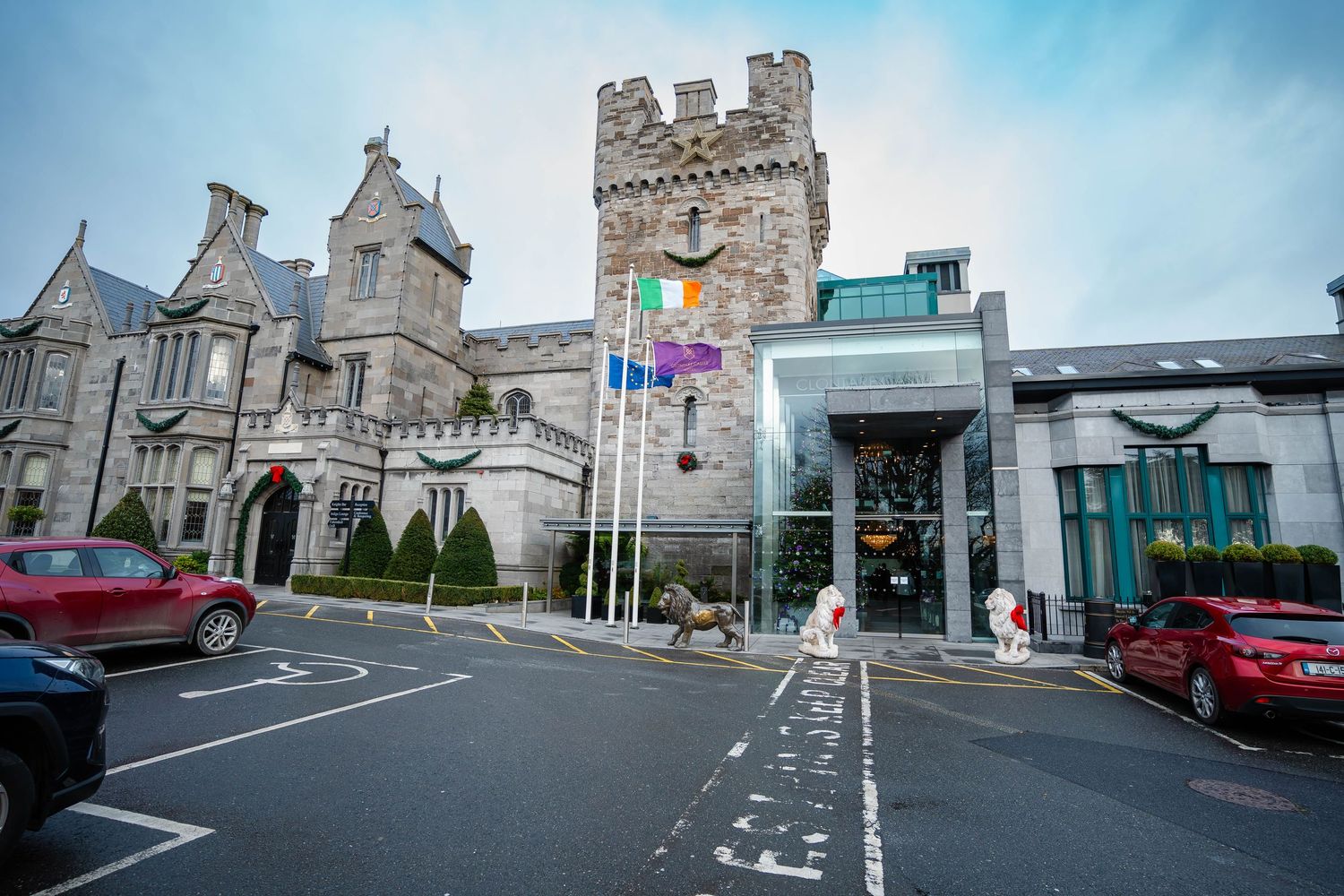 Exterior view of a grand stone building with modern architecture and parking area.