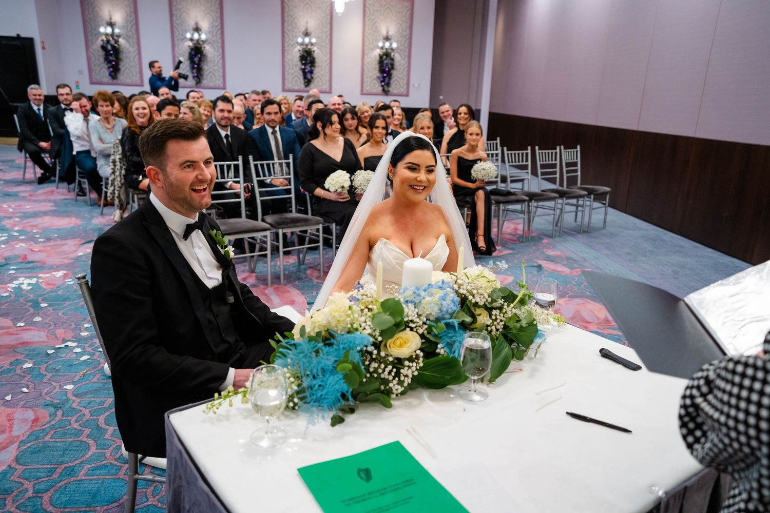 Wedding ceremony setup in an elegant ballroom with floral arrangements and guest seating.