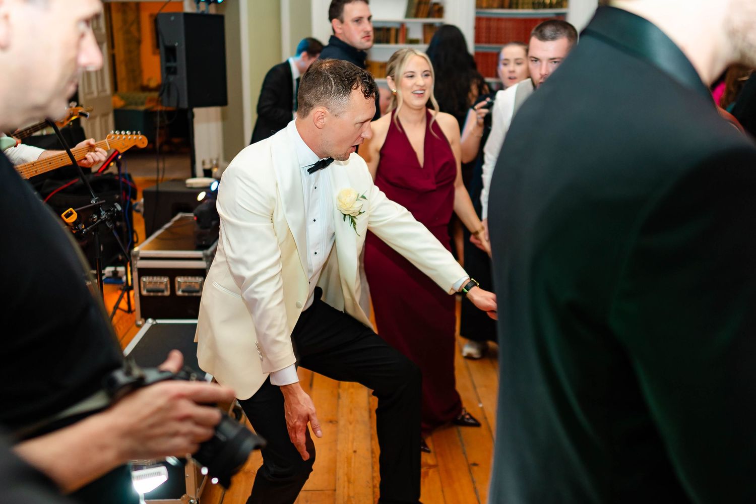 A group of dancers practice ballroom dancing steps together in a studio with wooden floors.