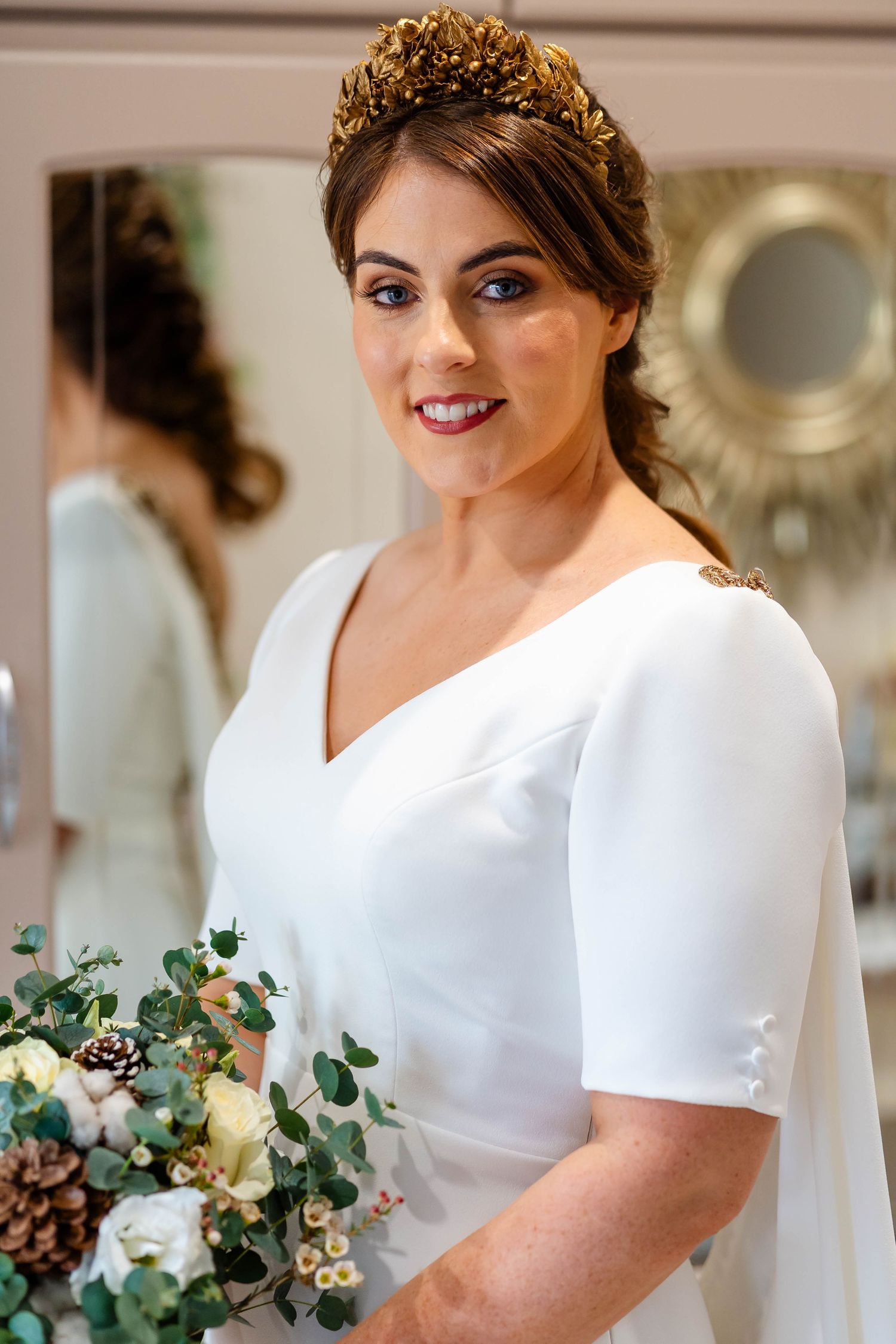 Bride in classic white wedding dress with short sleeves holding a green and white bouquet.