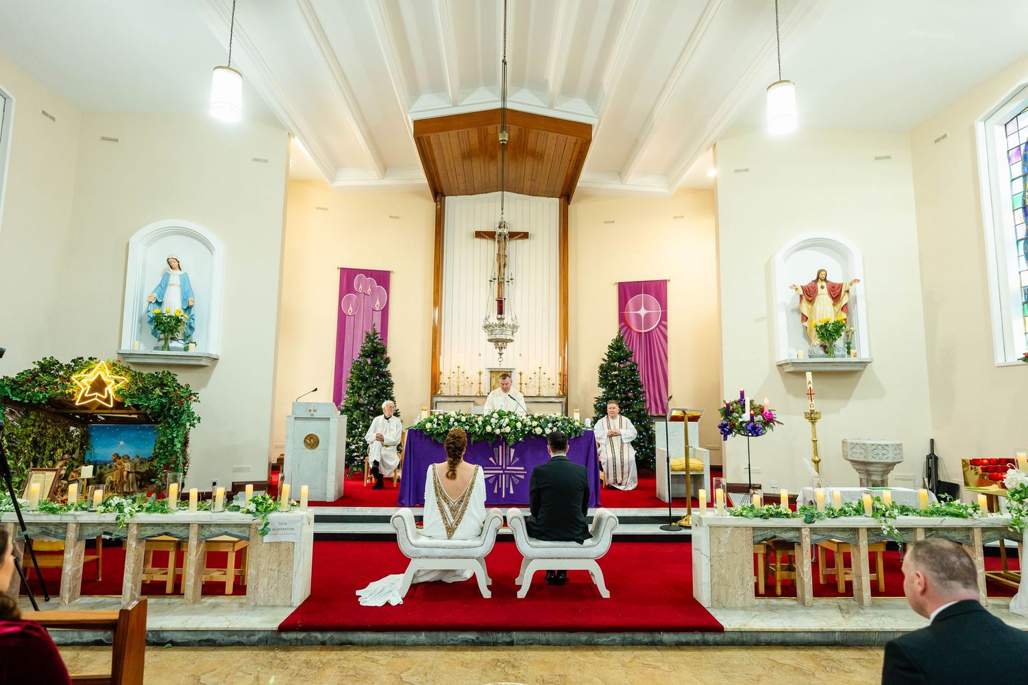Panoramic view of a church wedding ceremony with floral decorations and red carpet.