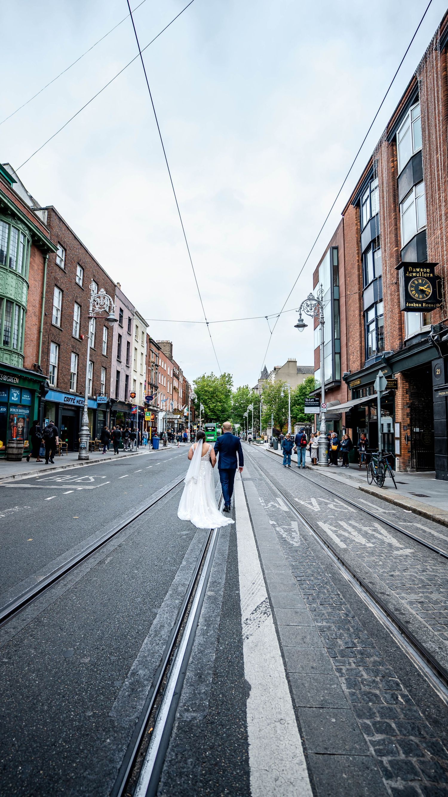 Cobblestone street lined with brick buildings and overhead power lines in Dublin.
