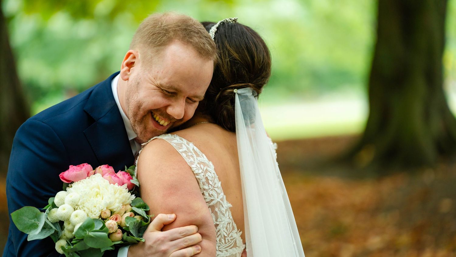 Emotional first look moment between newlyweds on a park pathway.