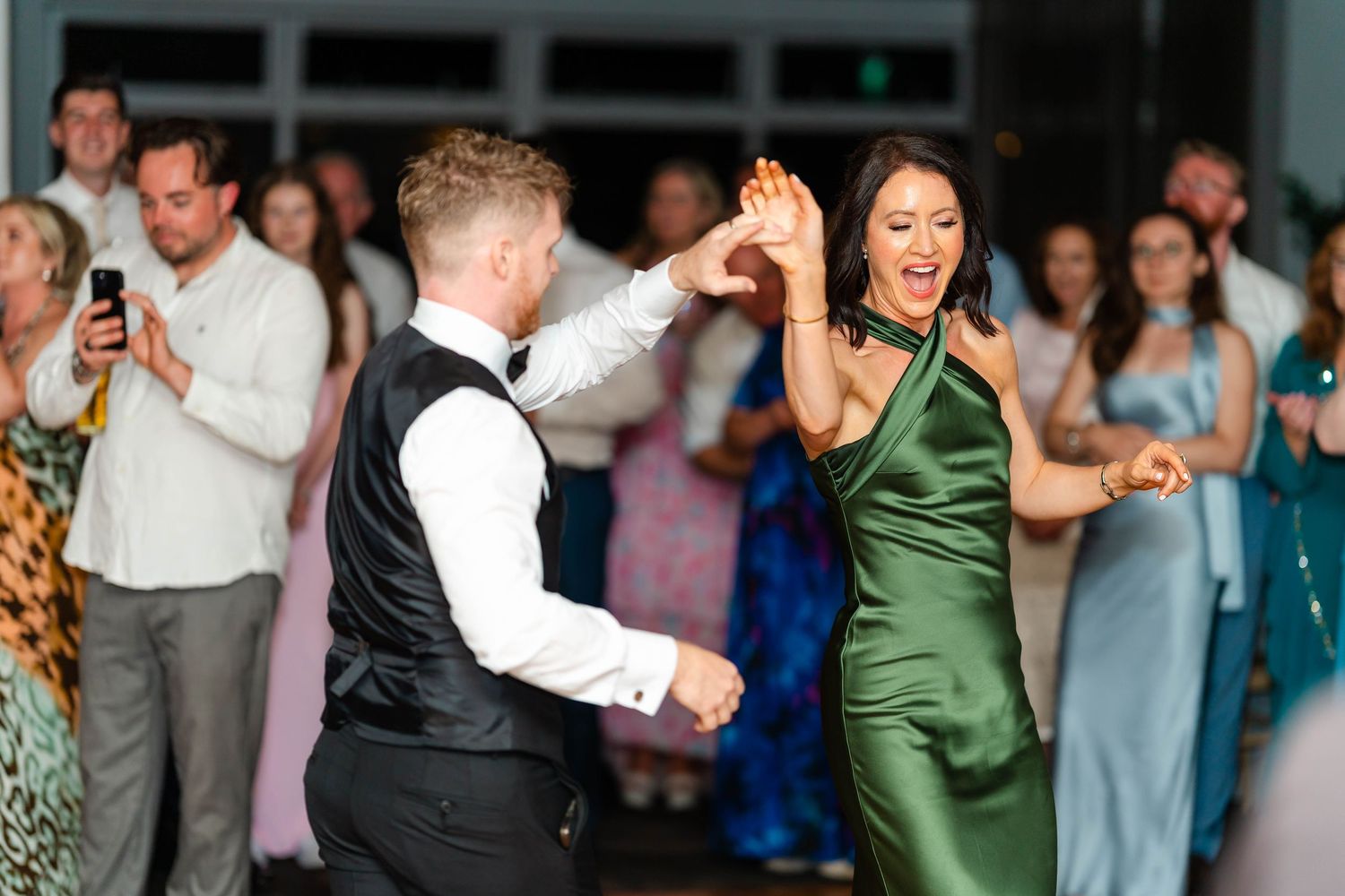 Party guests enjoying synchronized dance moves at an elegant indoor wedding celebration.