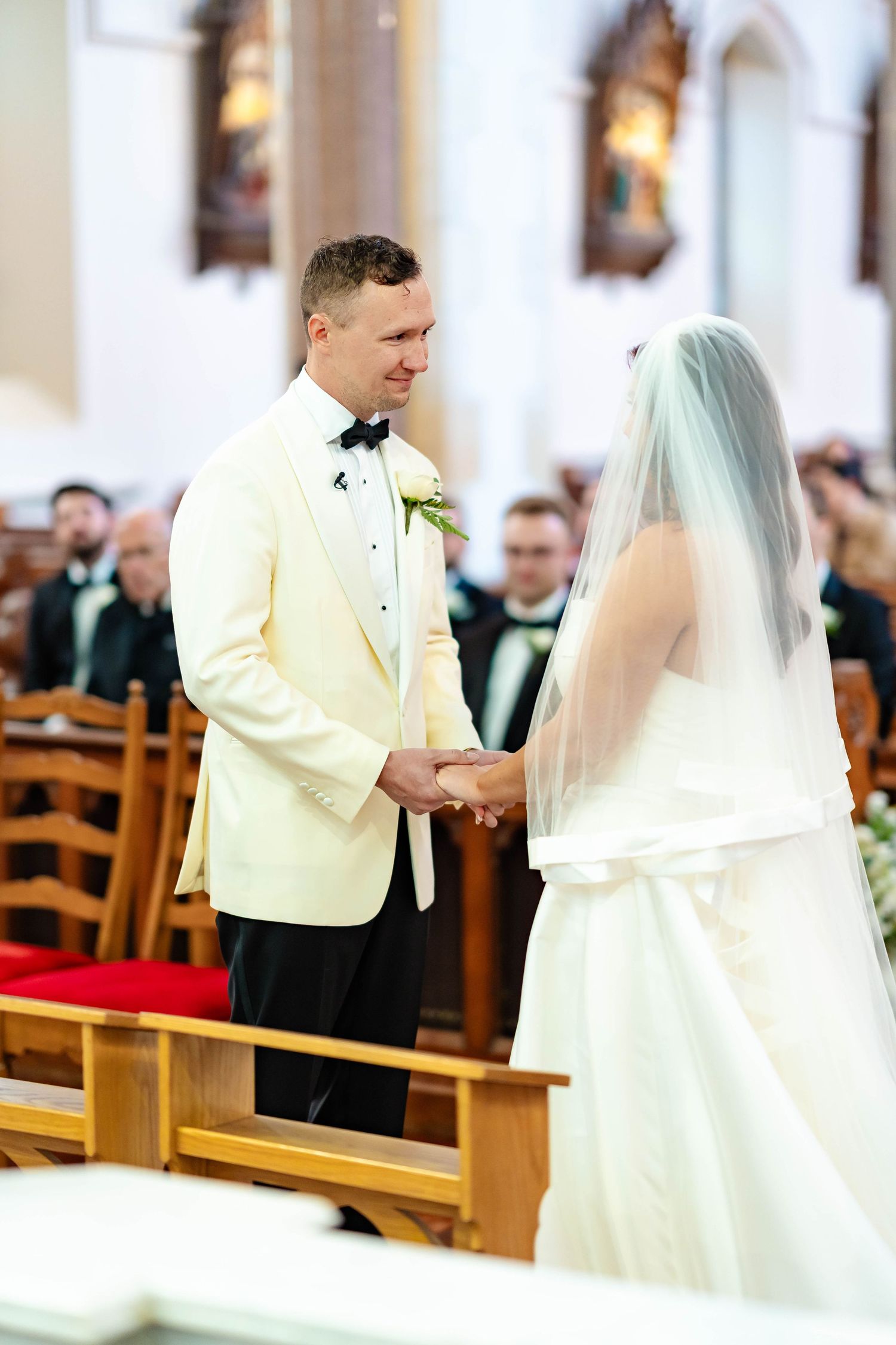 Wedding ceremony photos showing a couple exchanging rings in a church with wooden pews and soft lighting.