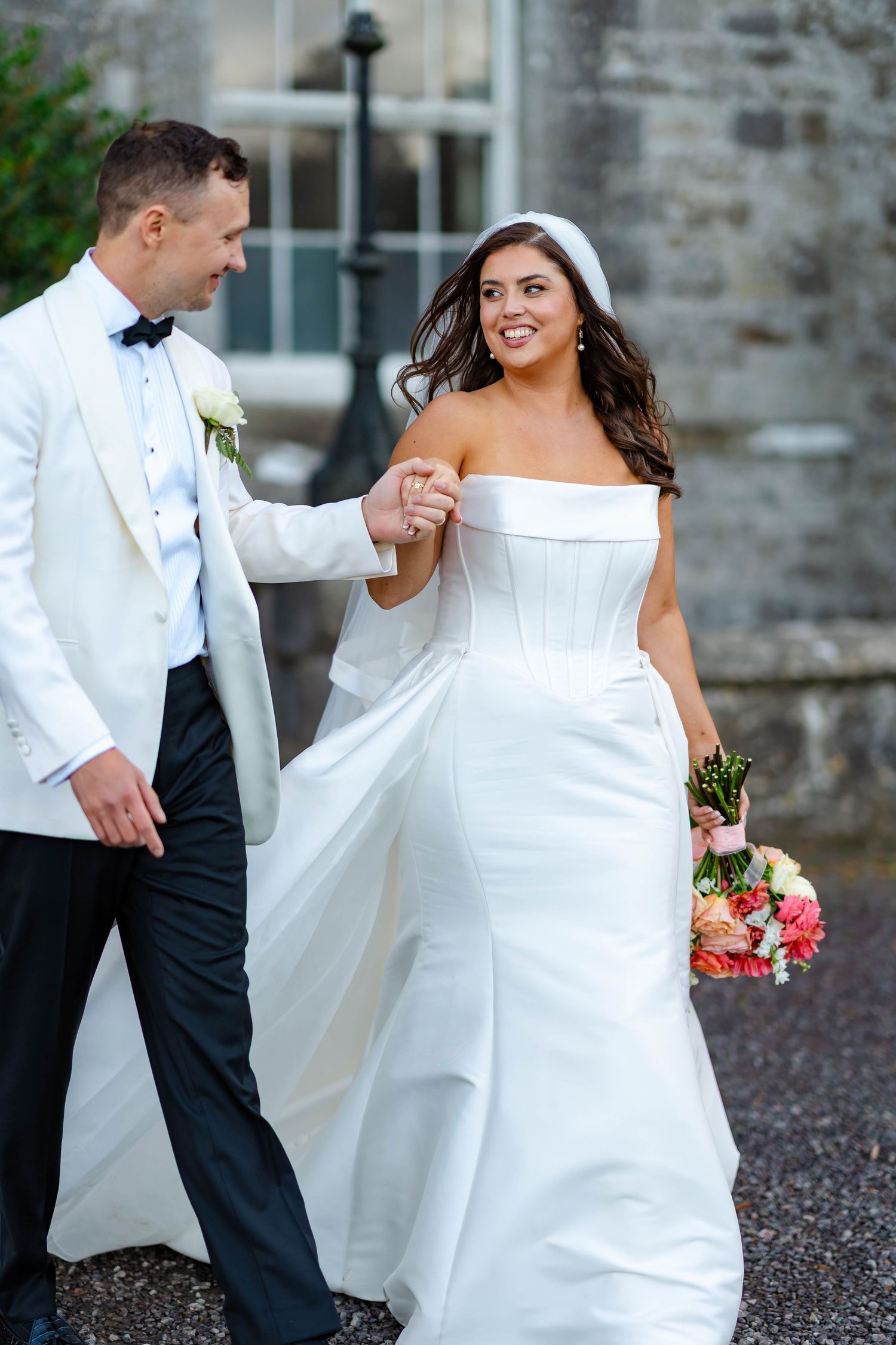 A romantic wedding photo series showing a couple in white formal attire dancing and embracing on stone grounds.
