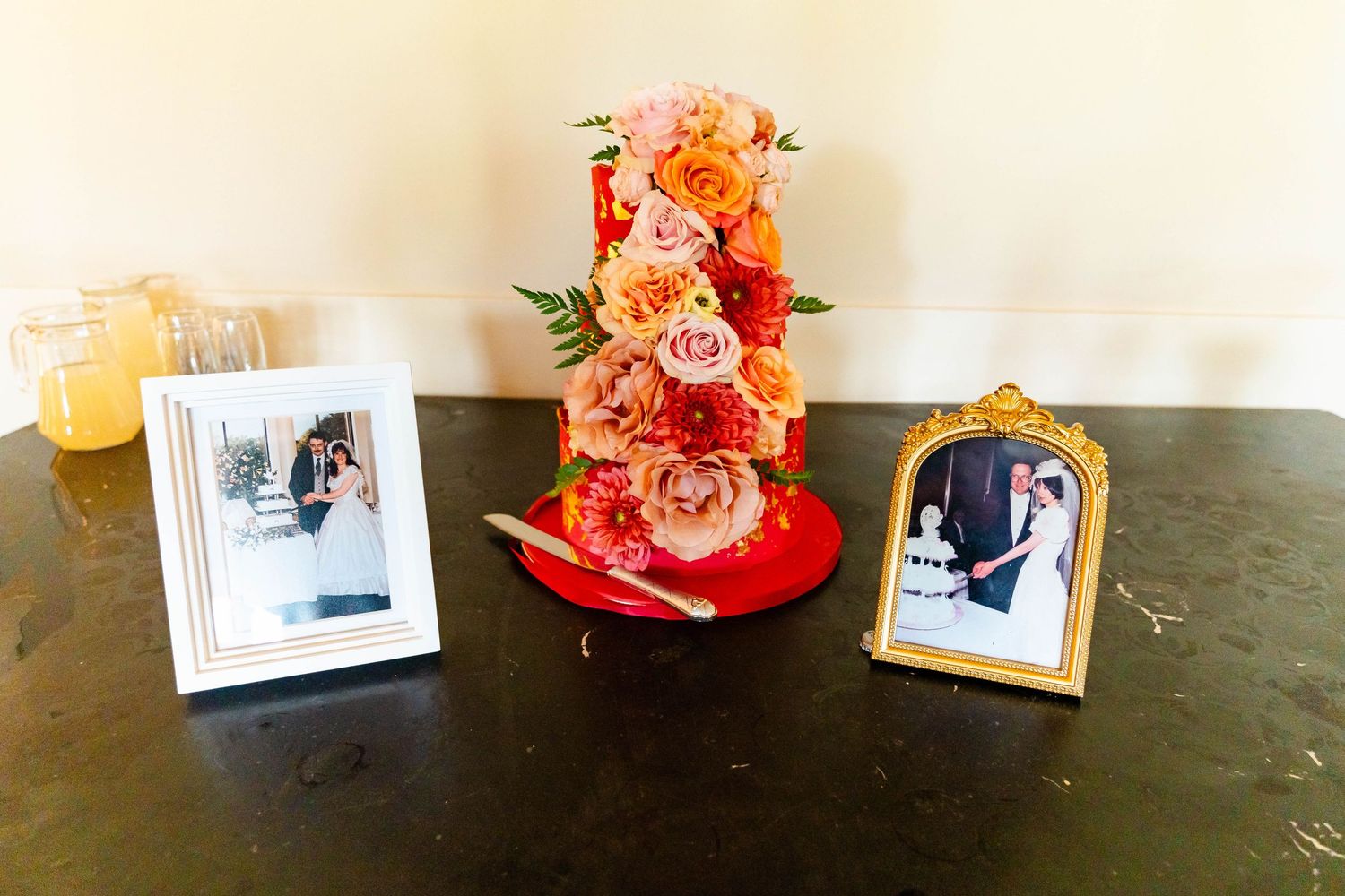 A row of framed photographs and floral arrangements displayed on a dark surface.